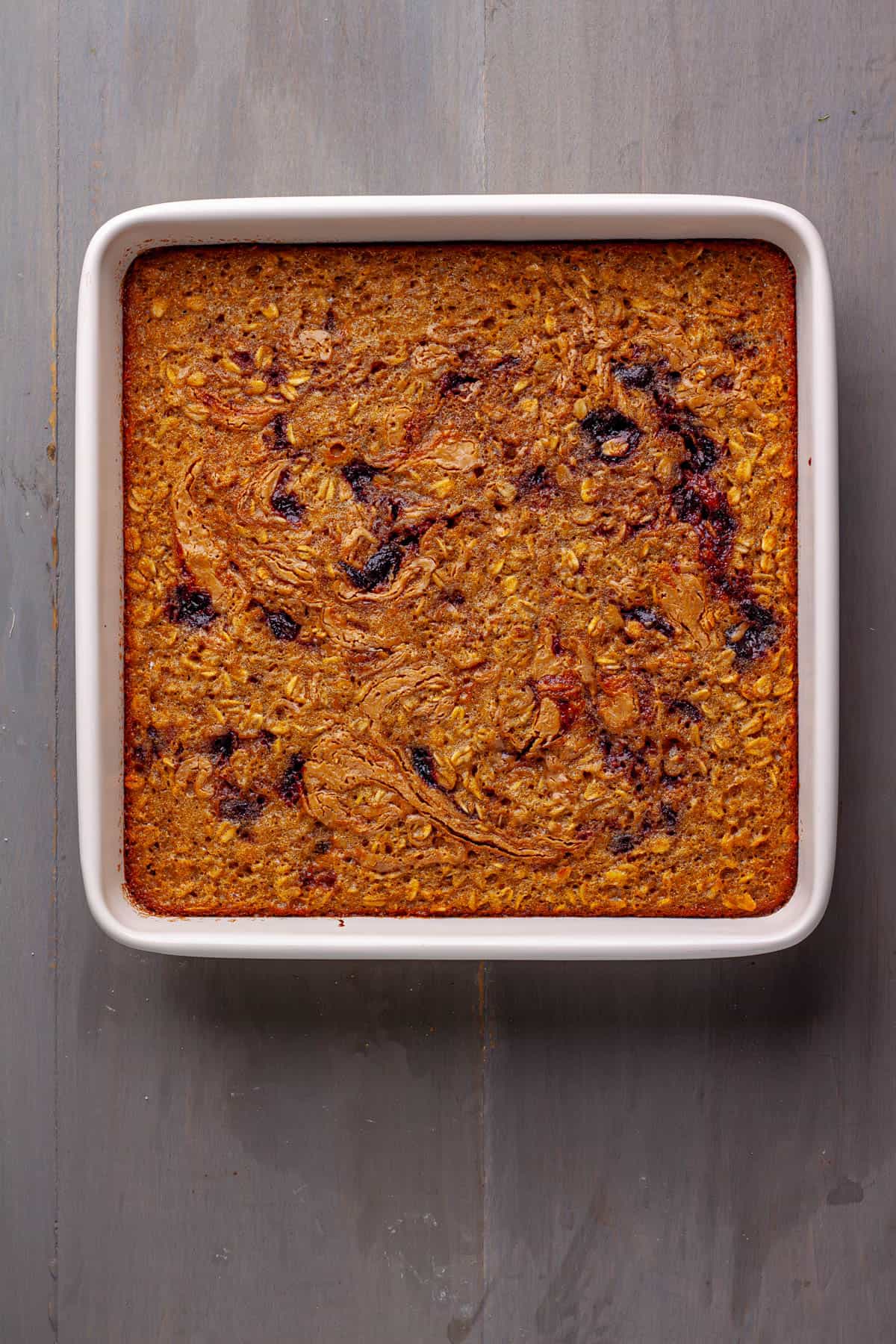 A cooked peanut butter and jam baked oatmeal in a square baking dish.