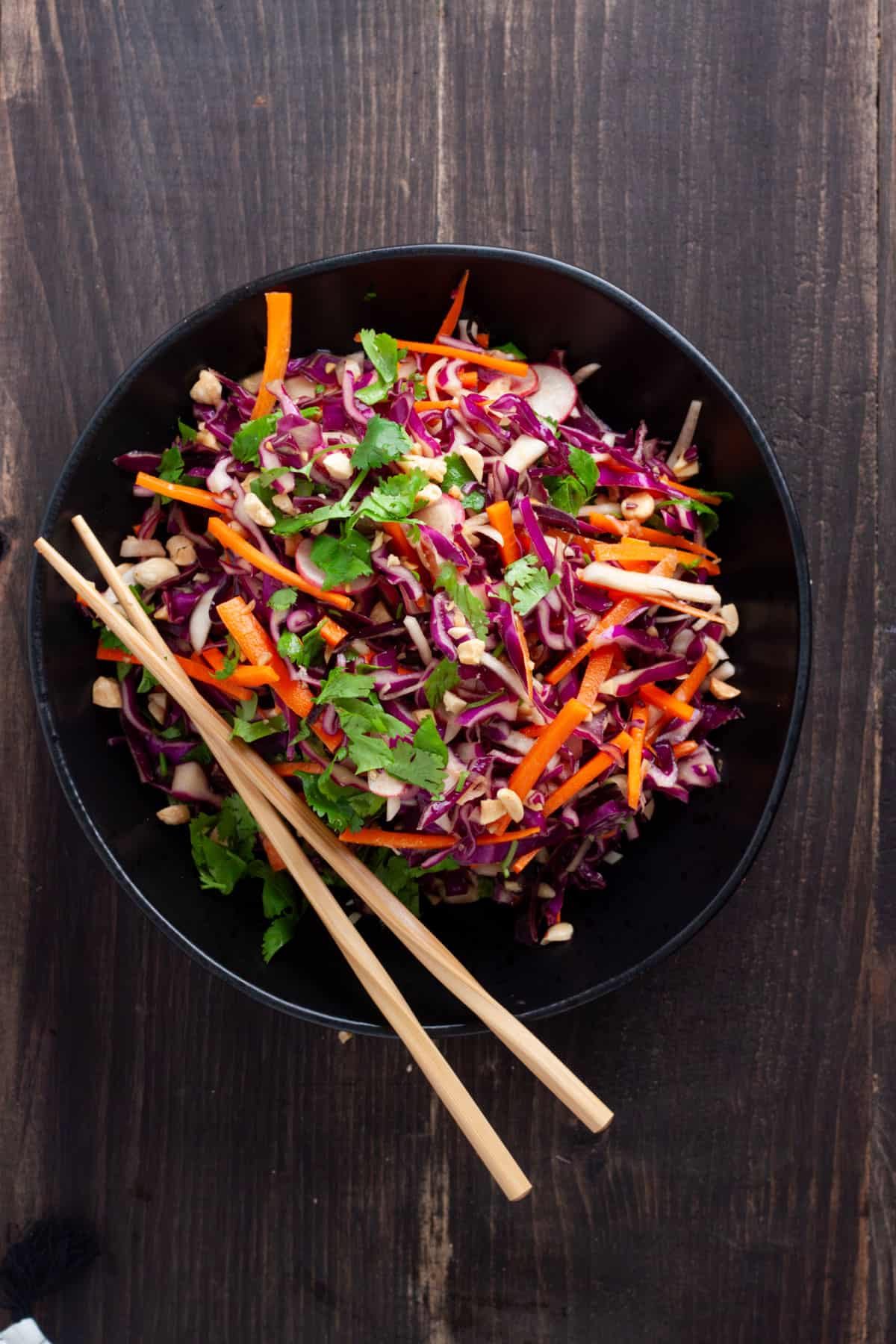 Purple cabbage slaw in a large black serving bowl with chopsticks to the side.