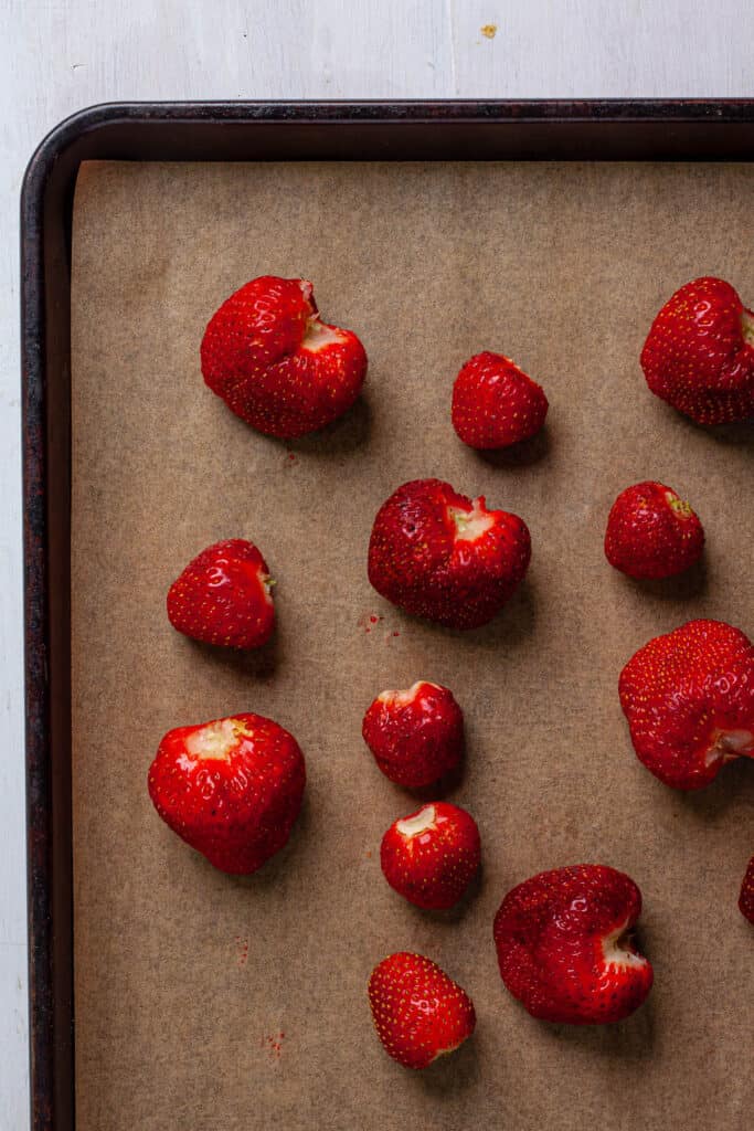 Fresh strawberries on a parchment lined baking sheet.