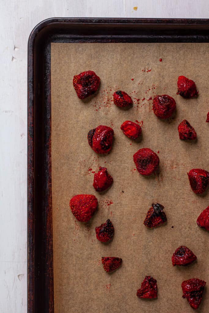 Roasted strawberries on a parchment lined baking sheet.