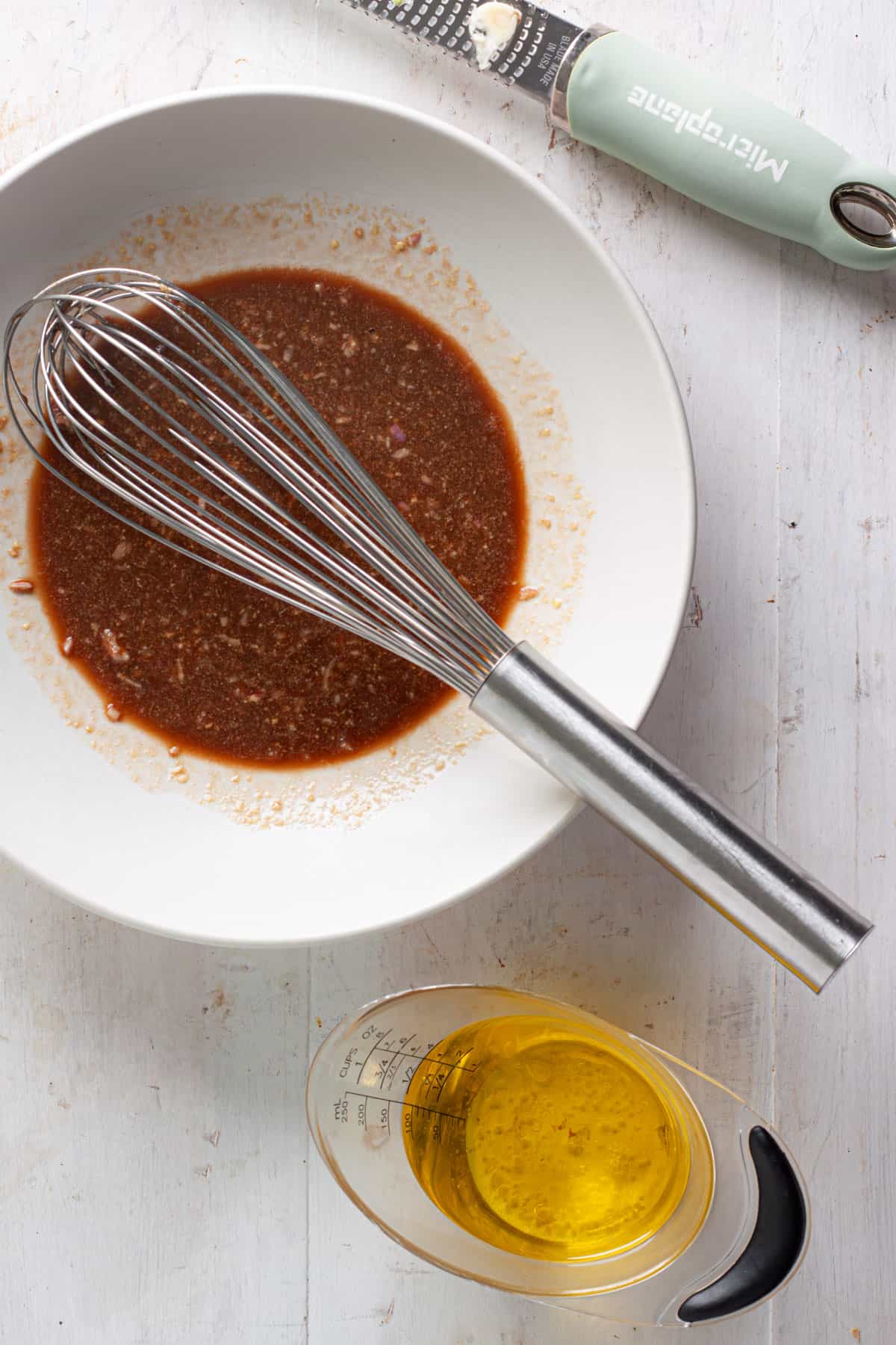 Basil balsamic vinaigrette getting whisked together in a medium bowl.