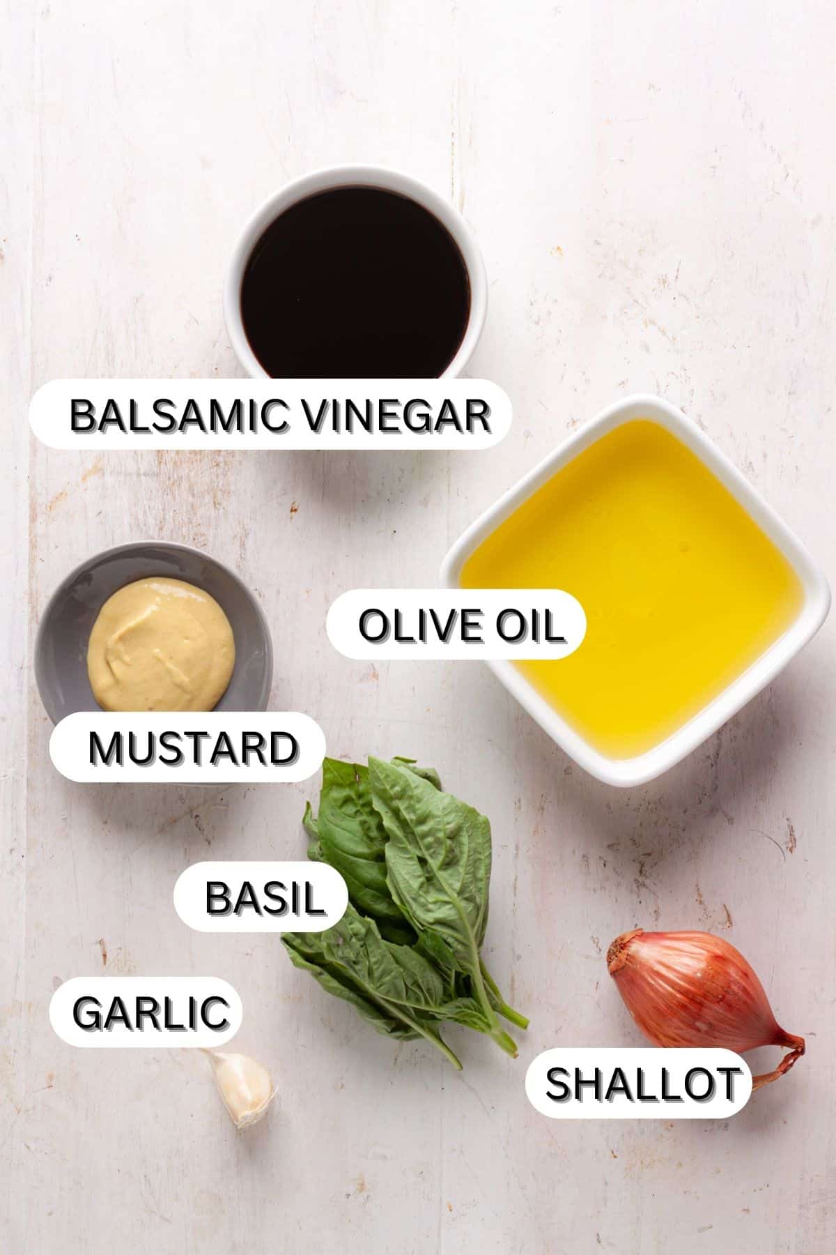 Ingredients for basil balsamic vinaigrette on a white table.