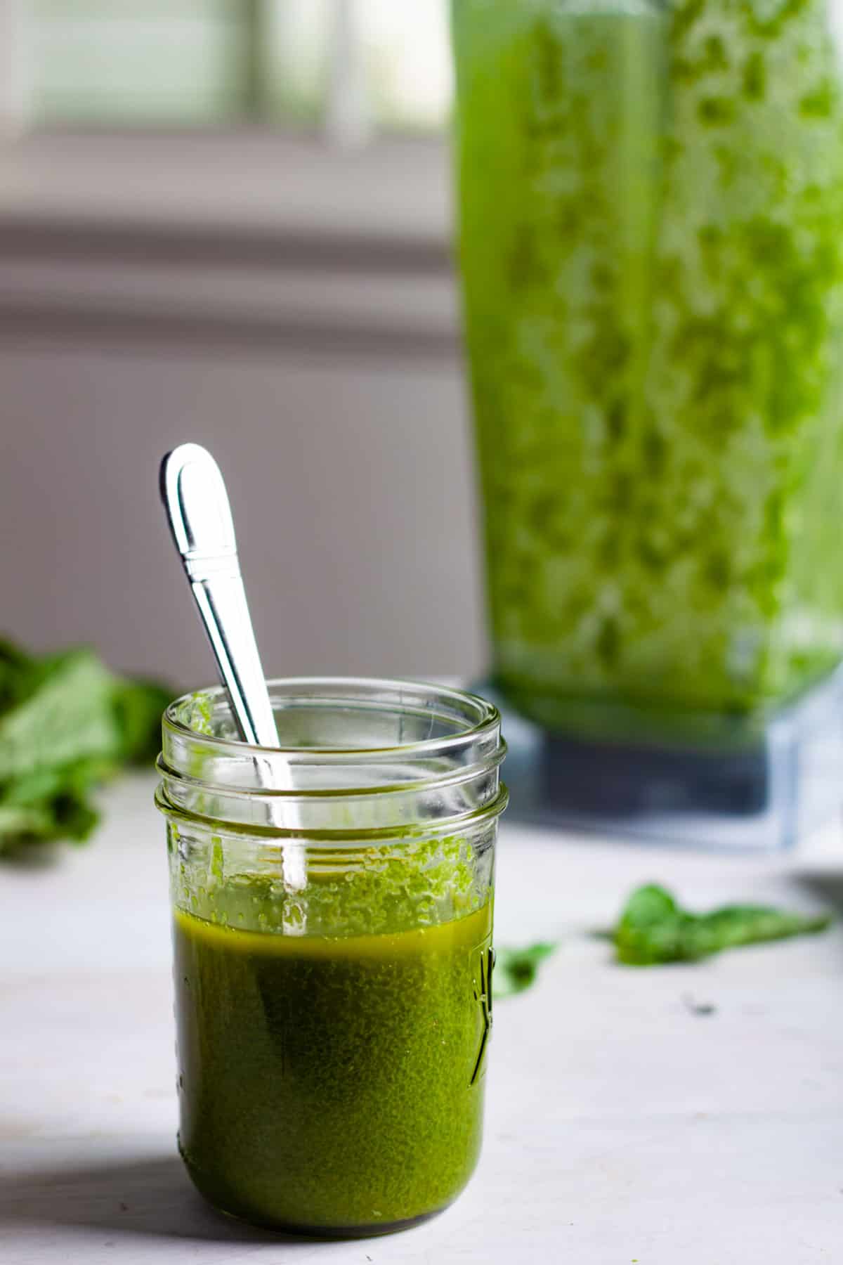 Basil vinaigrette in a mason jar with a spoon inside.