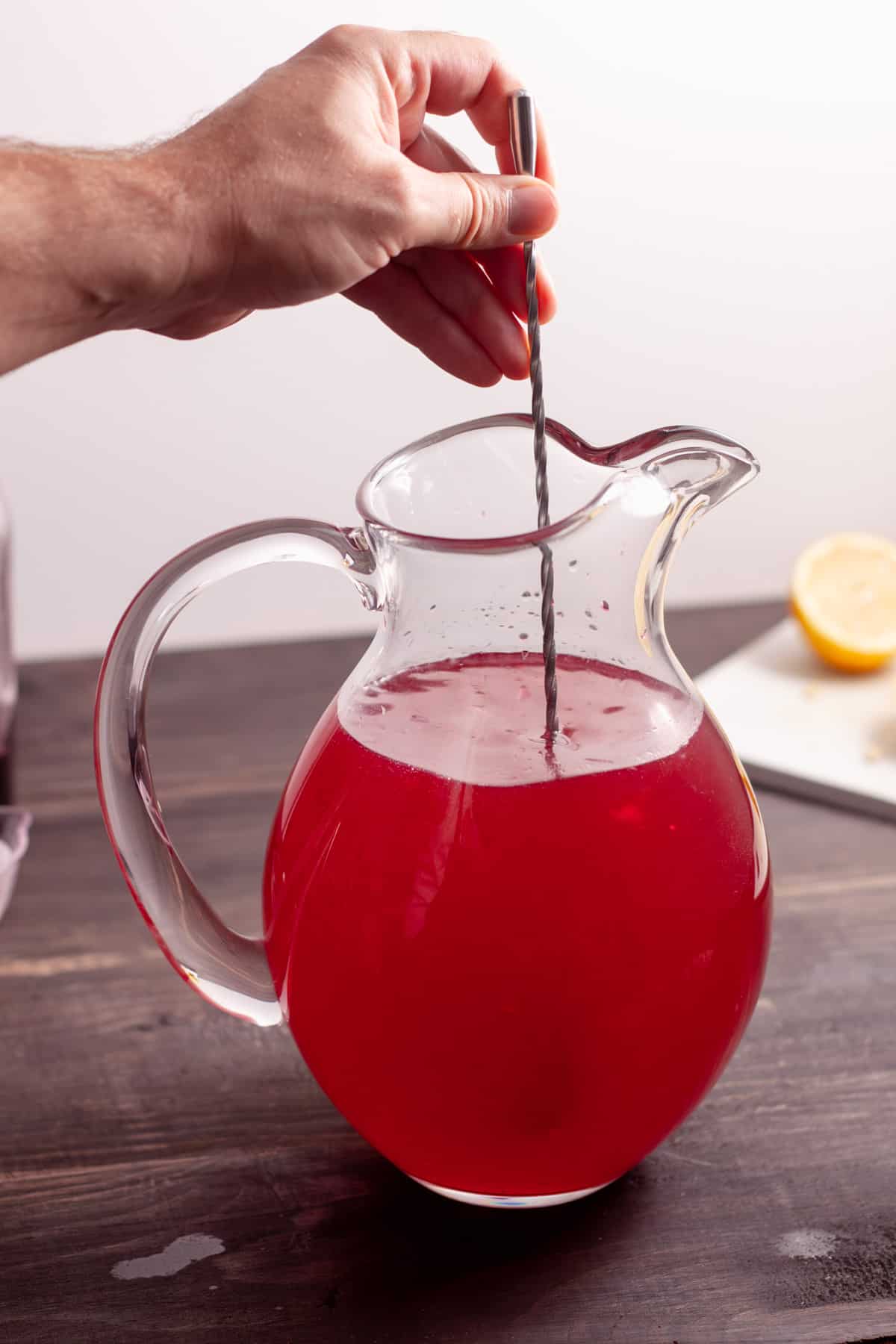 Homemade blueberry lemonade getting stirred together in a pitcher.
