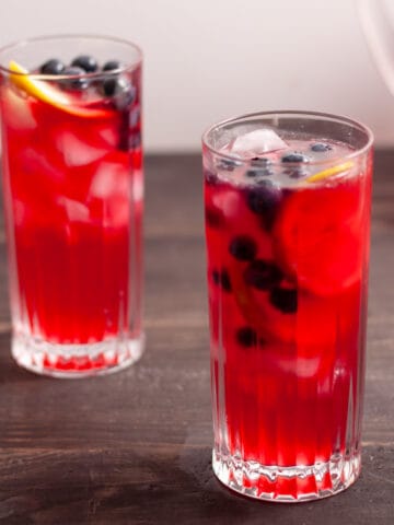 Two glasses of homemade blueberry lemonade garnished with blueberries and lemon.