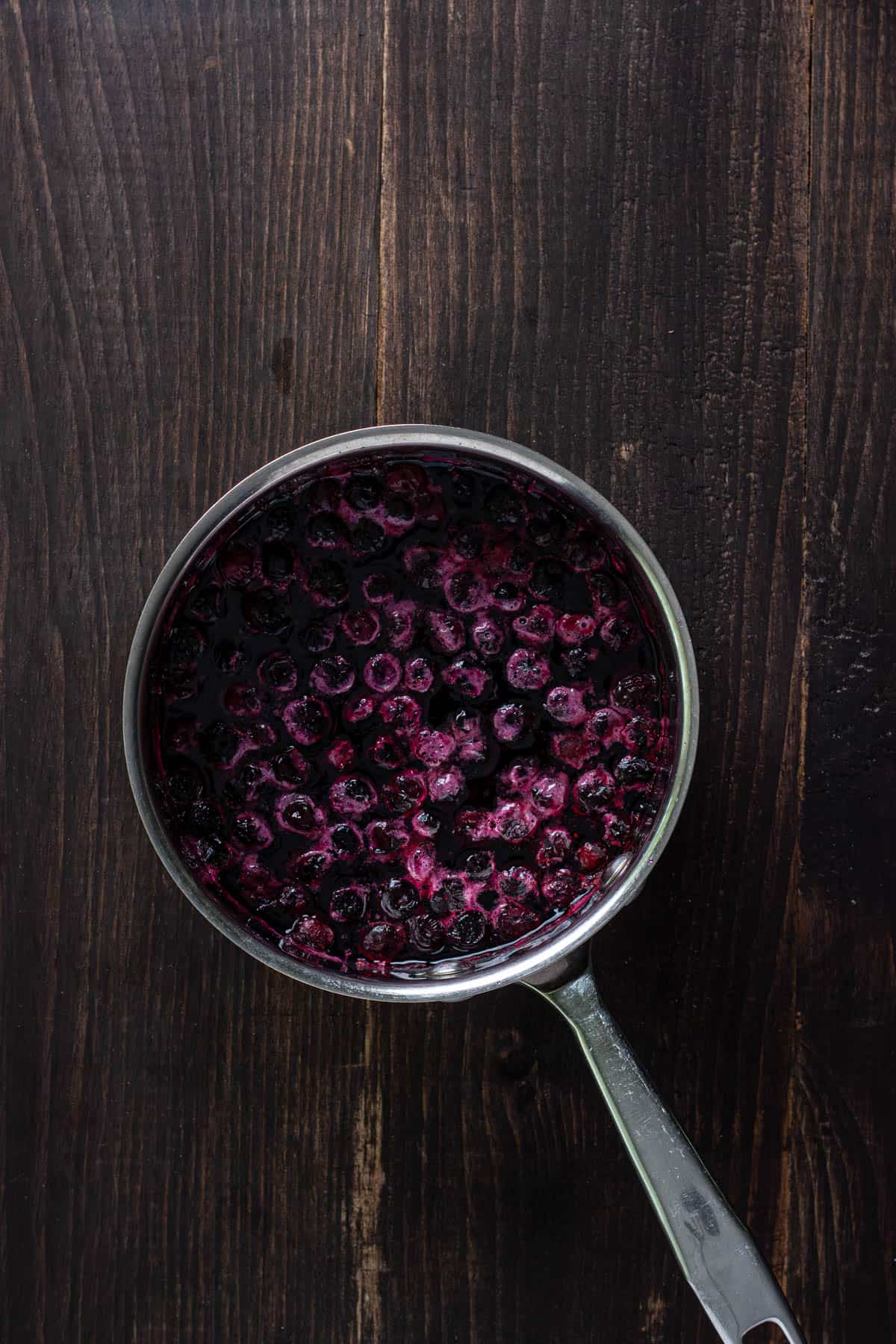 Blueberry simple syrup simmering in a small saucepan.