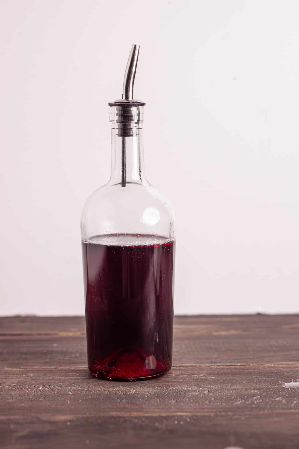 Blueberry simple syrup in a glass serving bottle.