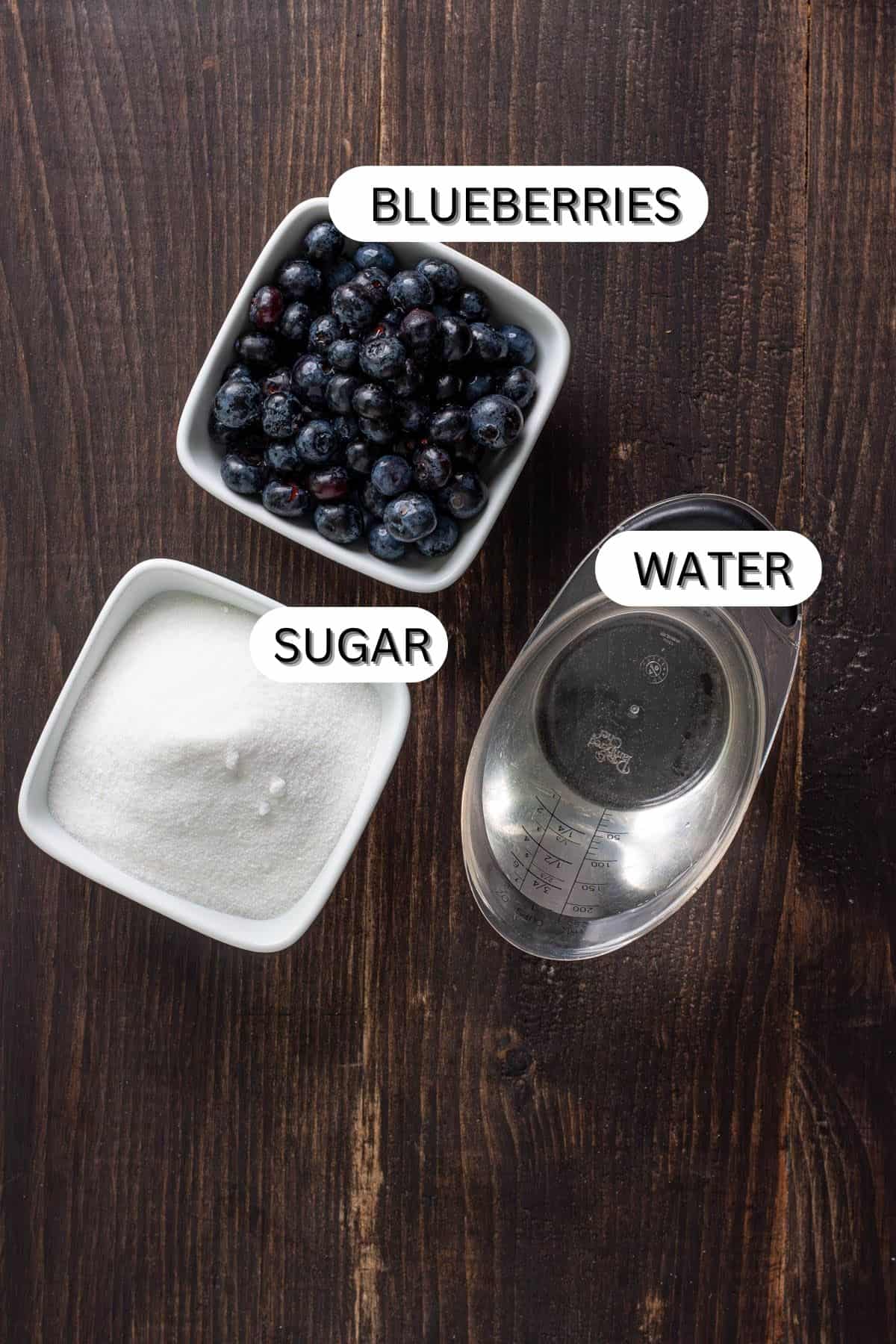 Ingredients for blueberry simple syrup on a dark table.