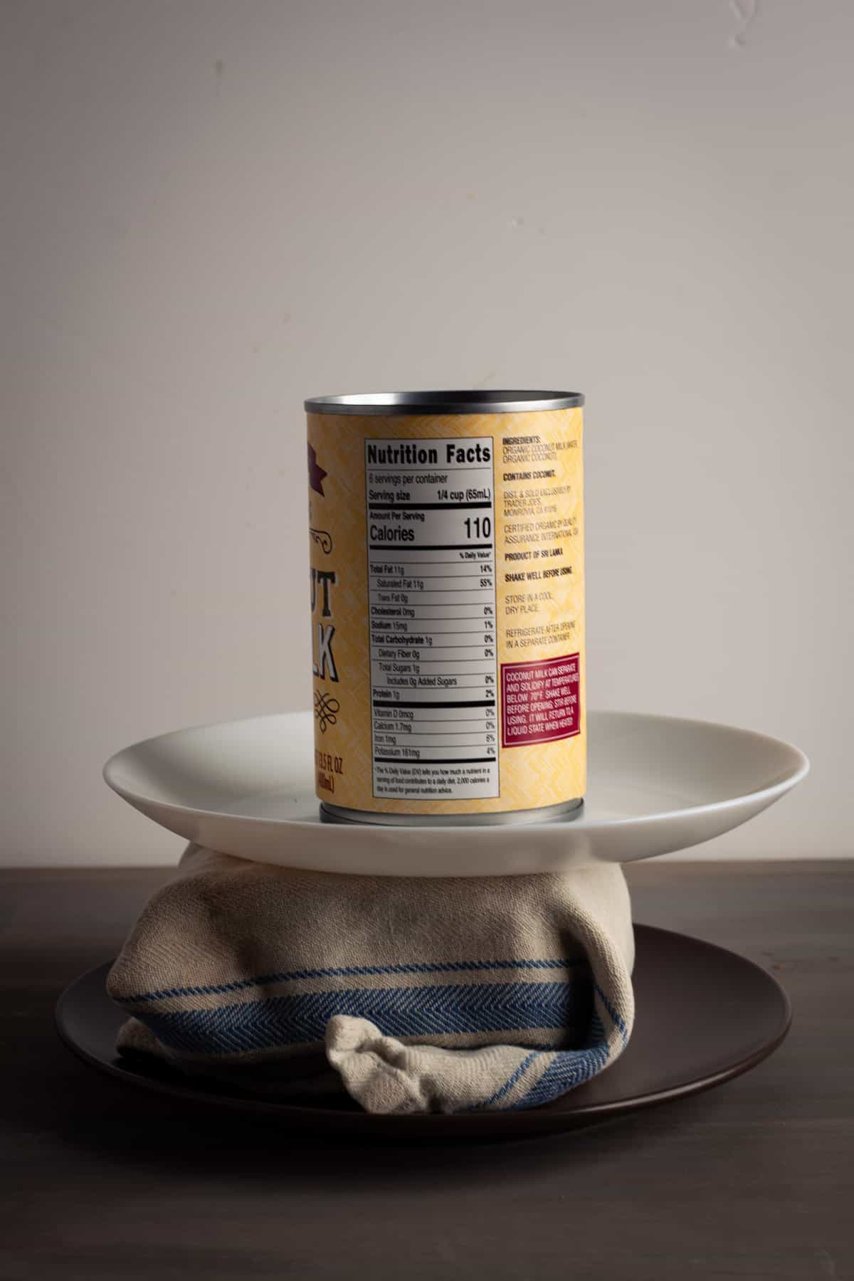 A block of tofu wrapped in a towel with a plate on top and a can pressing it down.