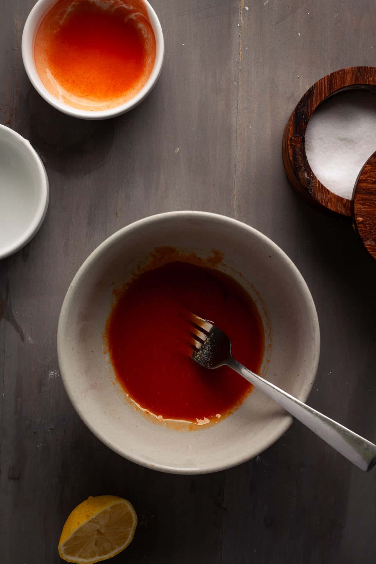 Vegan buffalo sauce getting mixed in a medium bowl.