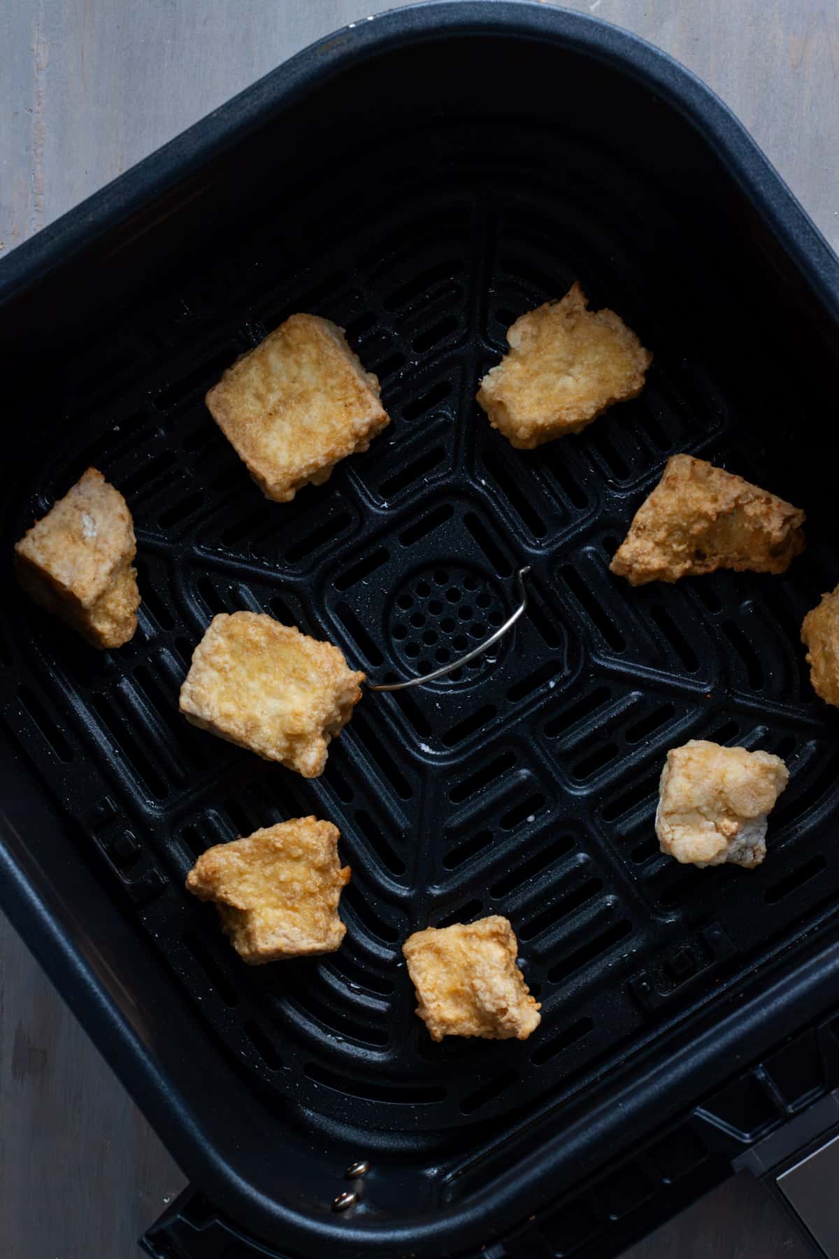 Crispy tofu in the basket of an air fryer. 