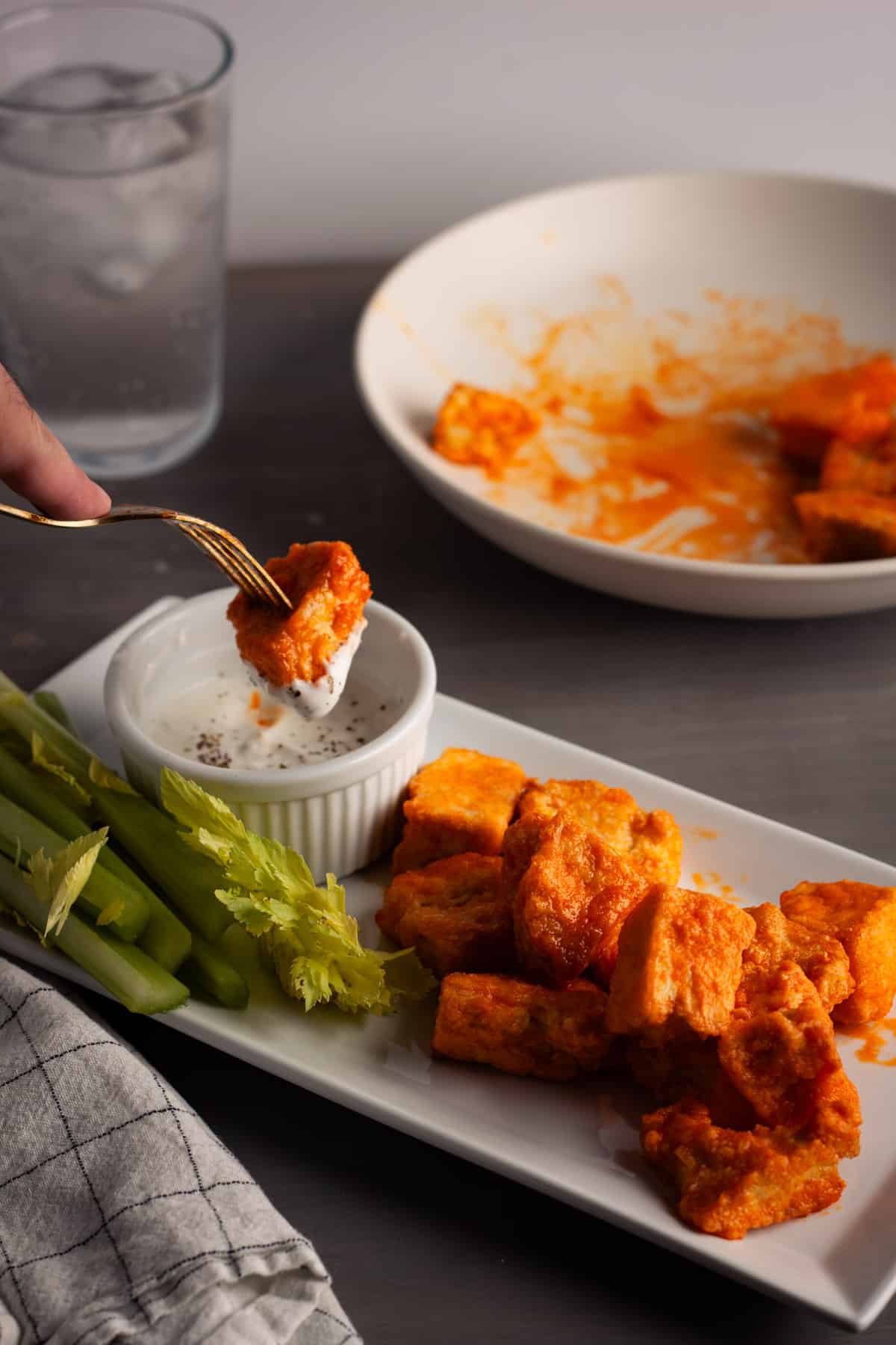A fork dipping crispy buffalo tofu in a ranch dressing.