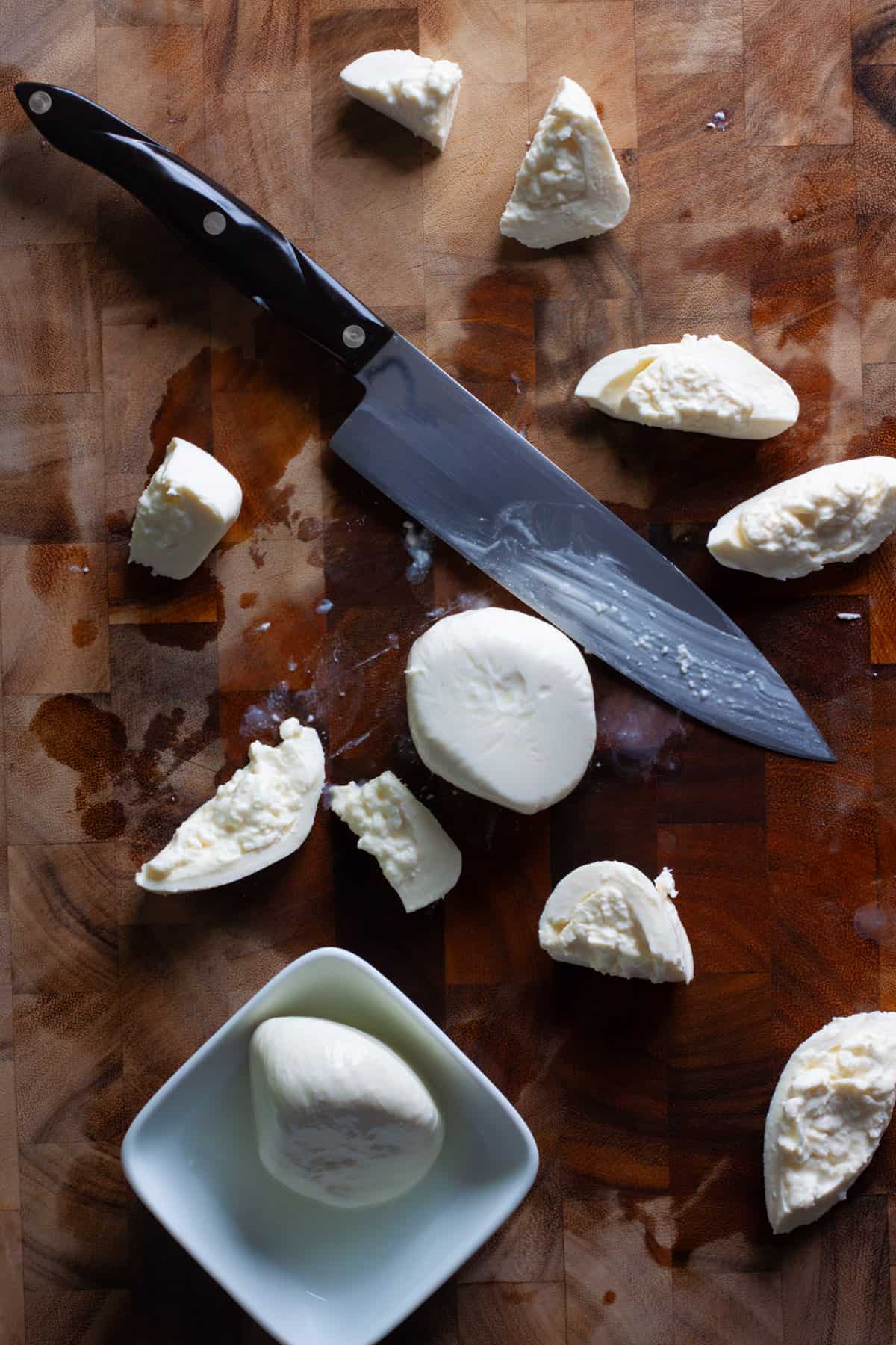 Burrata sliced on a cutting board for a caprese salad.