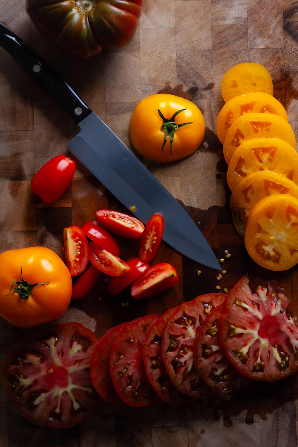 Heirloom tomatoes sliced on a cutting board to assemble a caprese salad.