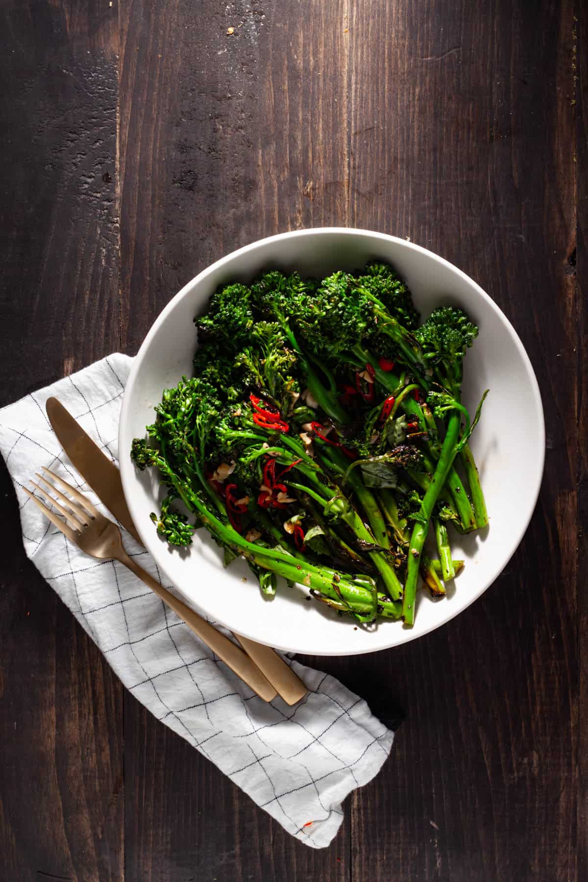 Charred broccolini with chili peppers and garlic in a serving bowl.
