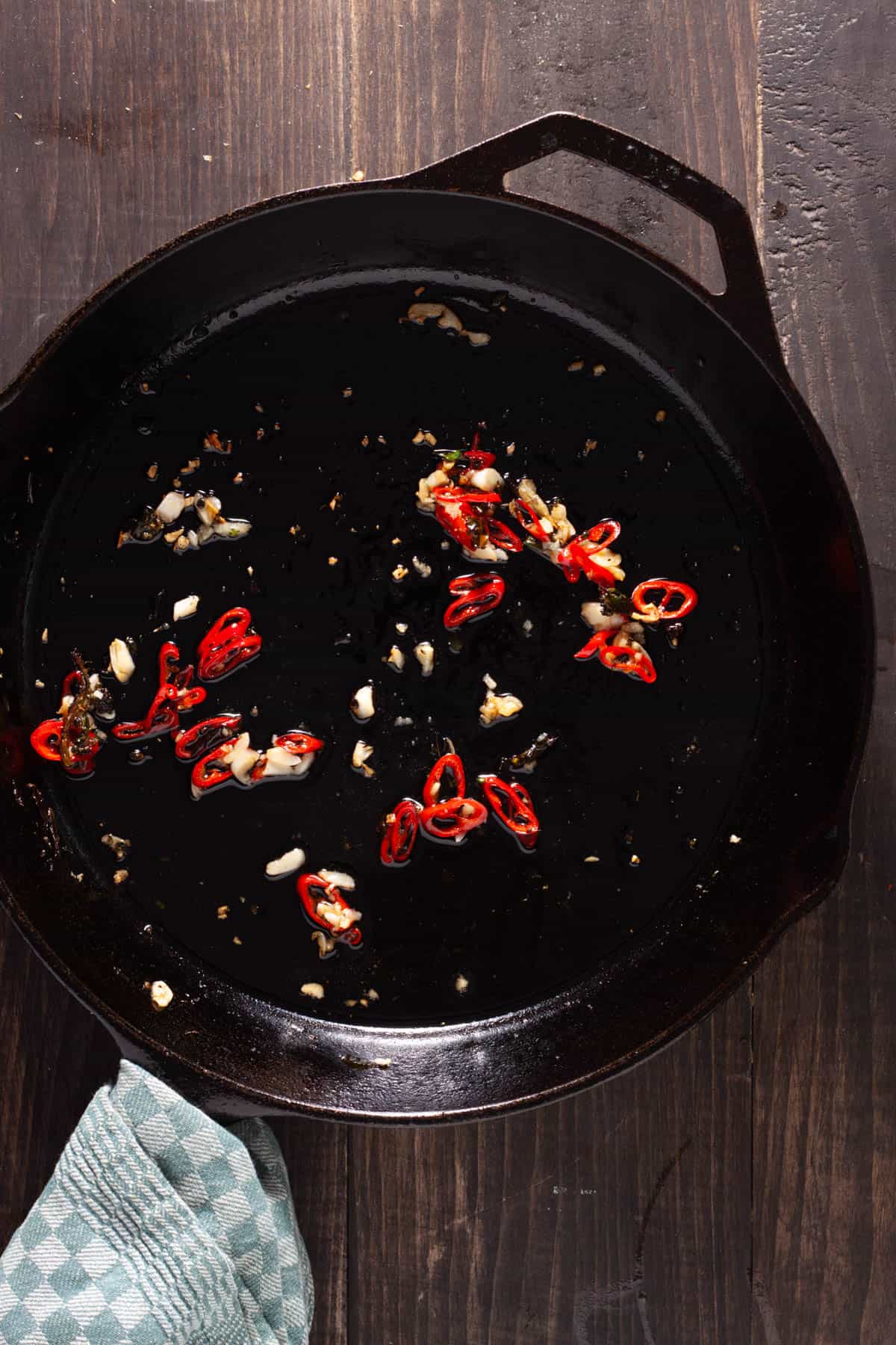 Chili peppers and garlic cooking in a large cast iron skillet.