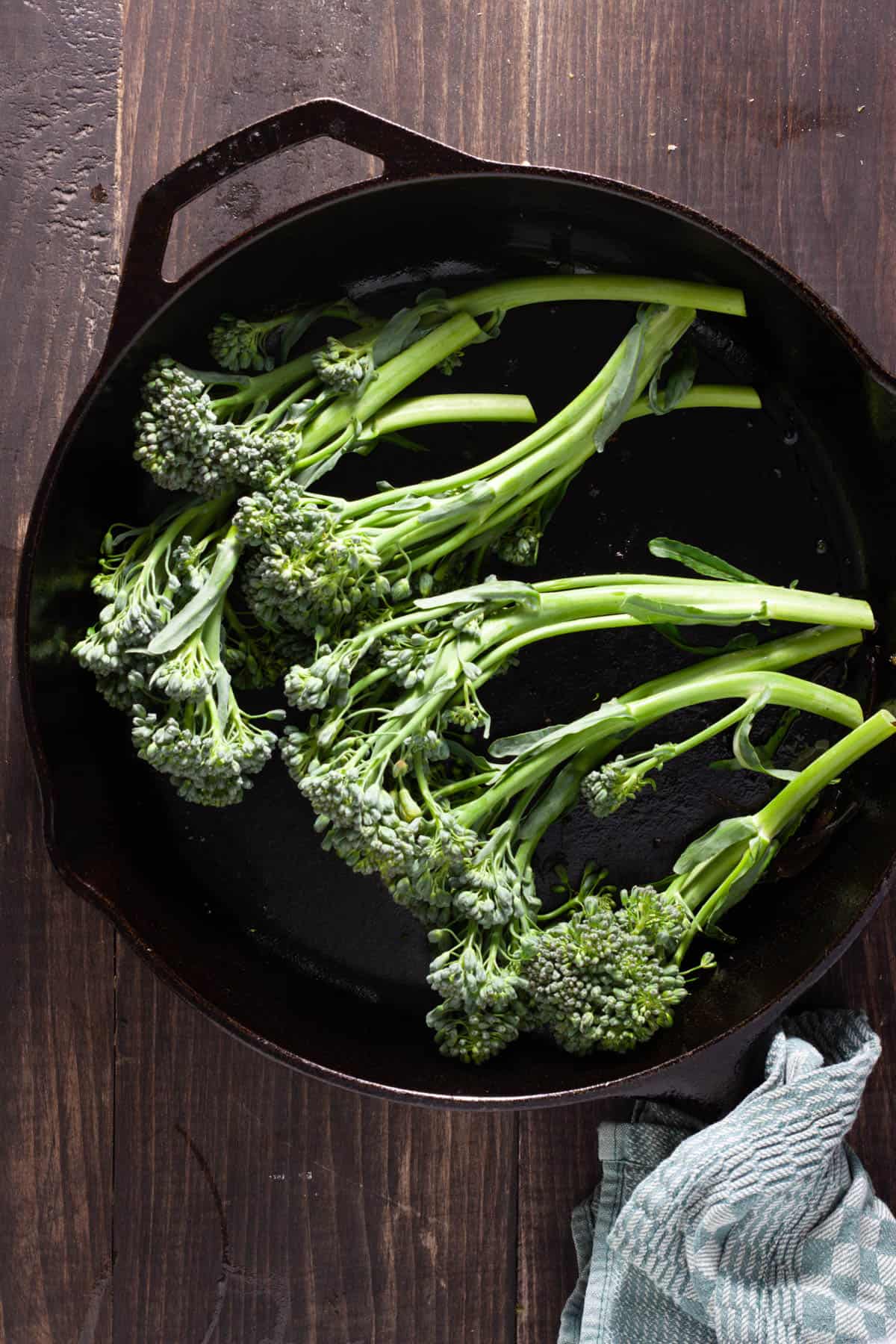 Trimmed broccolini in a large cast iron skillet getting ready to be seared.