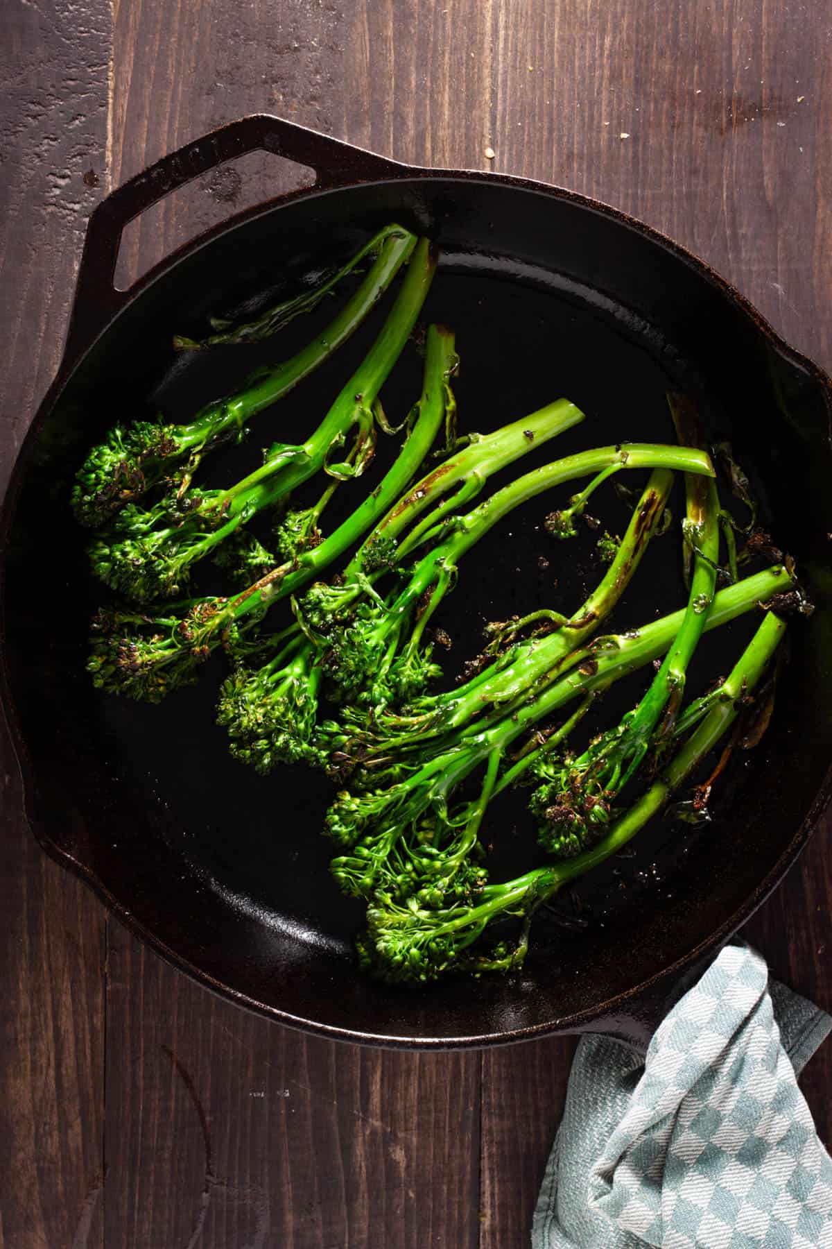 Broccolini getting seared in a large cast iron skillet.