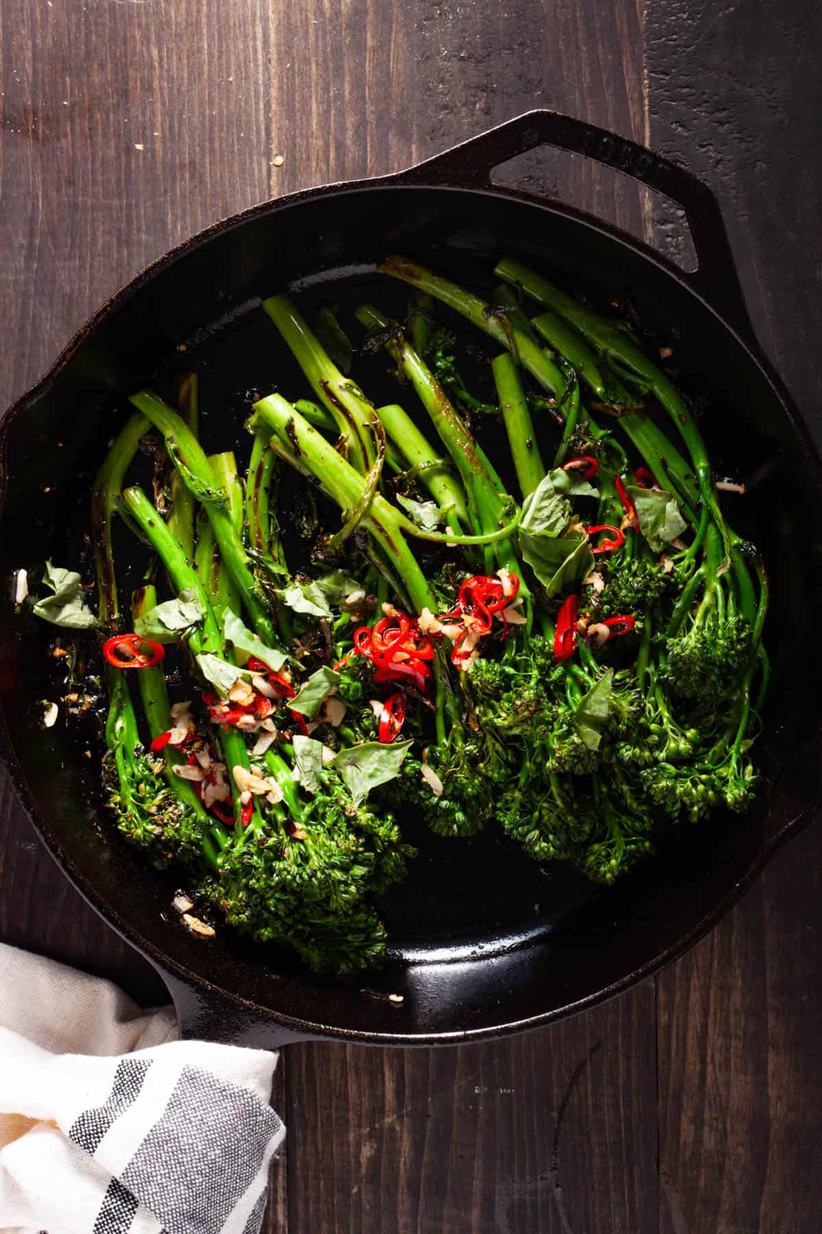 Charred broccolini topped with chili and garlic in a cast iron skillet.