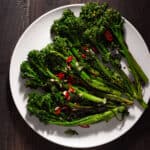 Charred broccolini topped with garlic and chili peppers in a serving bowl.