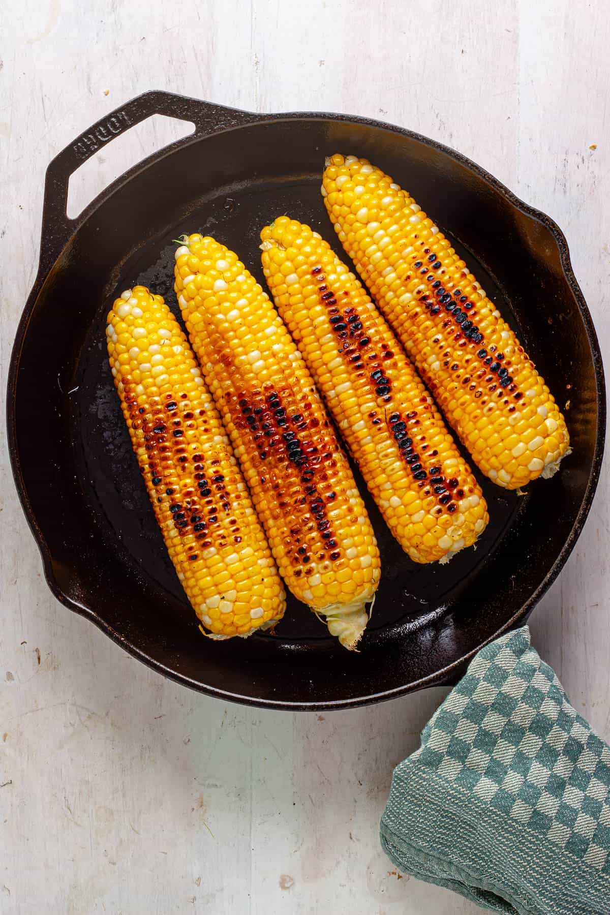 Charred corn on the cob in a skillet.