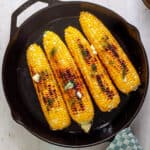 Skillet charred corn on the cob topped with butter and dill.