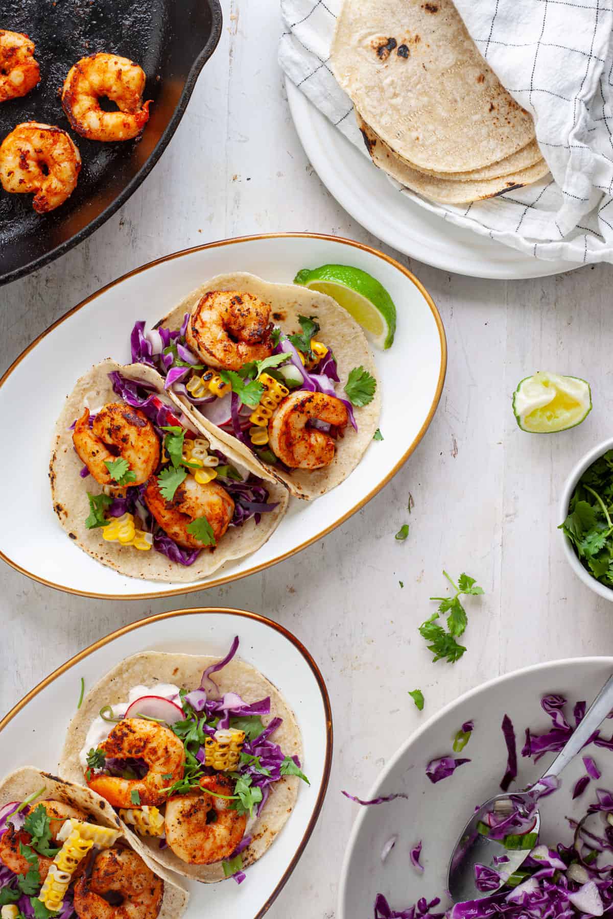 Chili lime shrimp tacos on plates with garnishes off to the side.