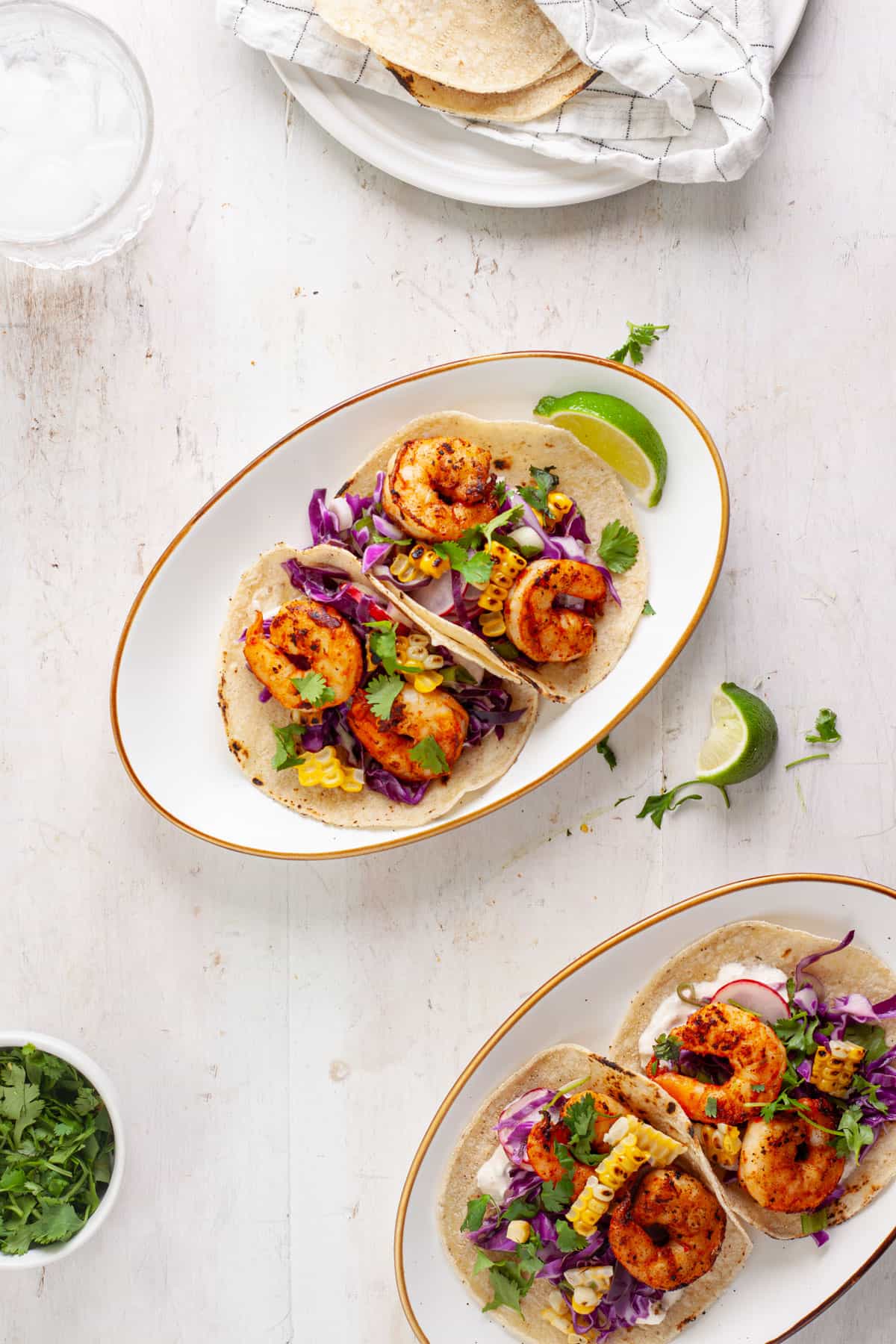 A serving of chili lime shrimp tacos on a small plate with another serving to the side.
