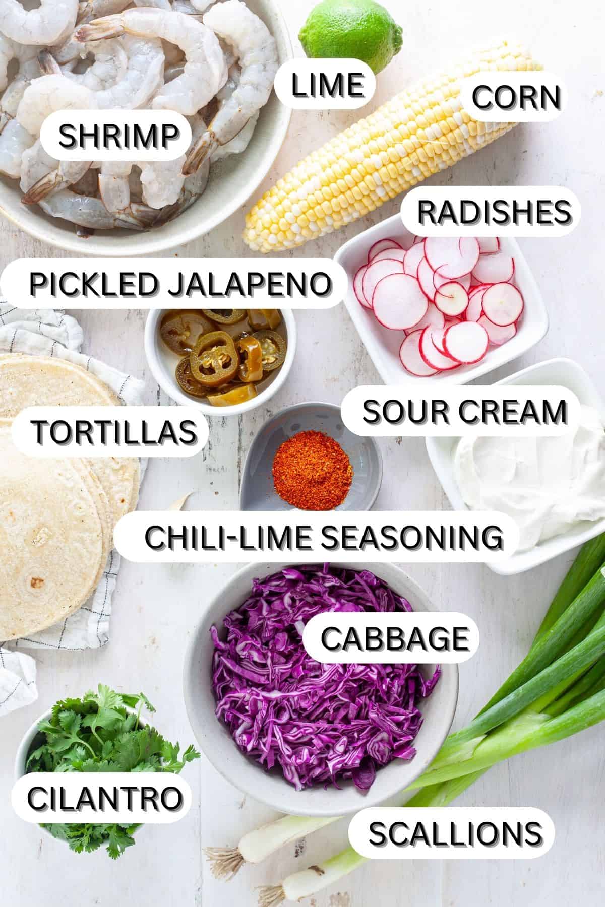Ingredients for chili lime shrimp tacos on a white table.