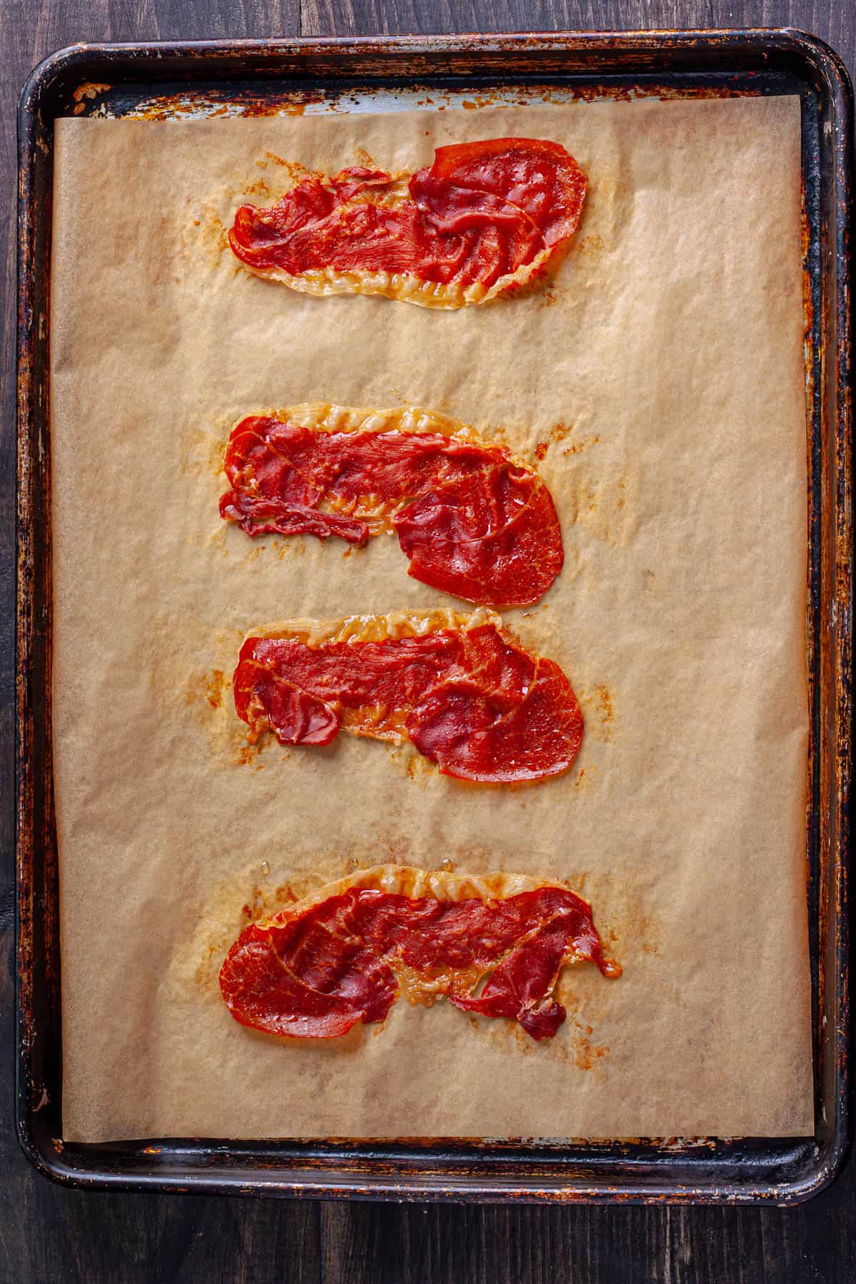 Crispy cooked prosciutto on a parchment lined baking sheet.