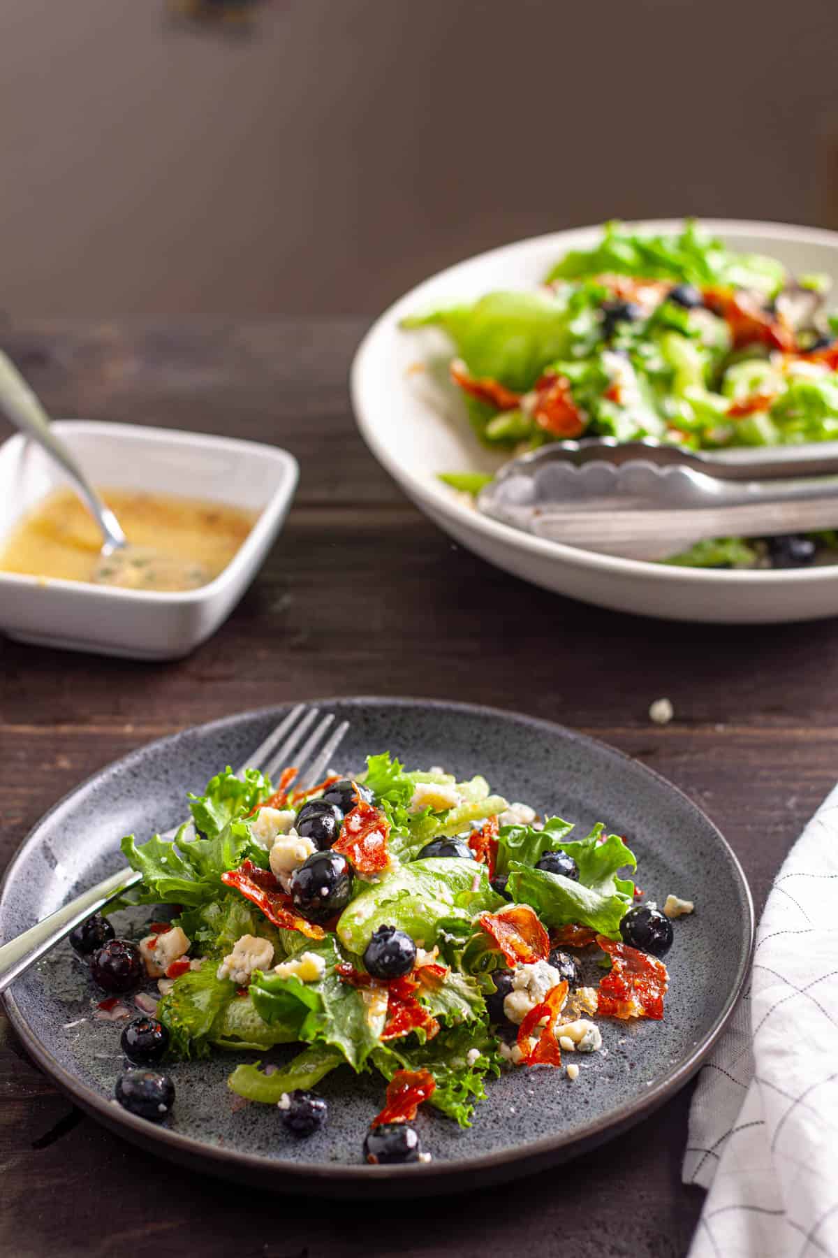 A small plate with crispy prosciutto, blueberry and blue cheese salad.