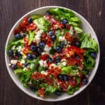 Crispy prosciutto, blueberry and blue cheese salad in a white serving bowl.