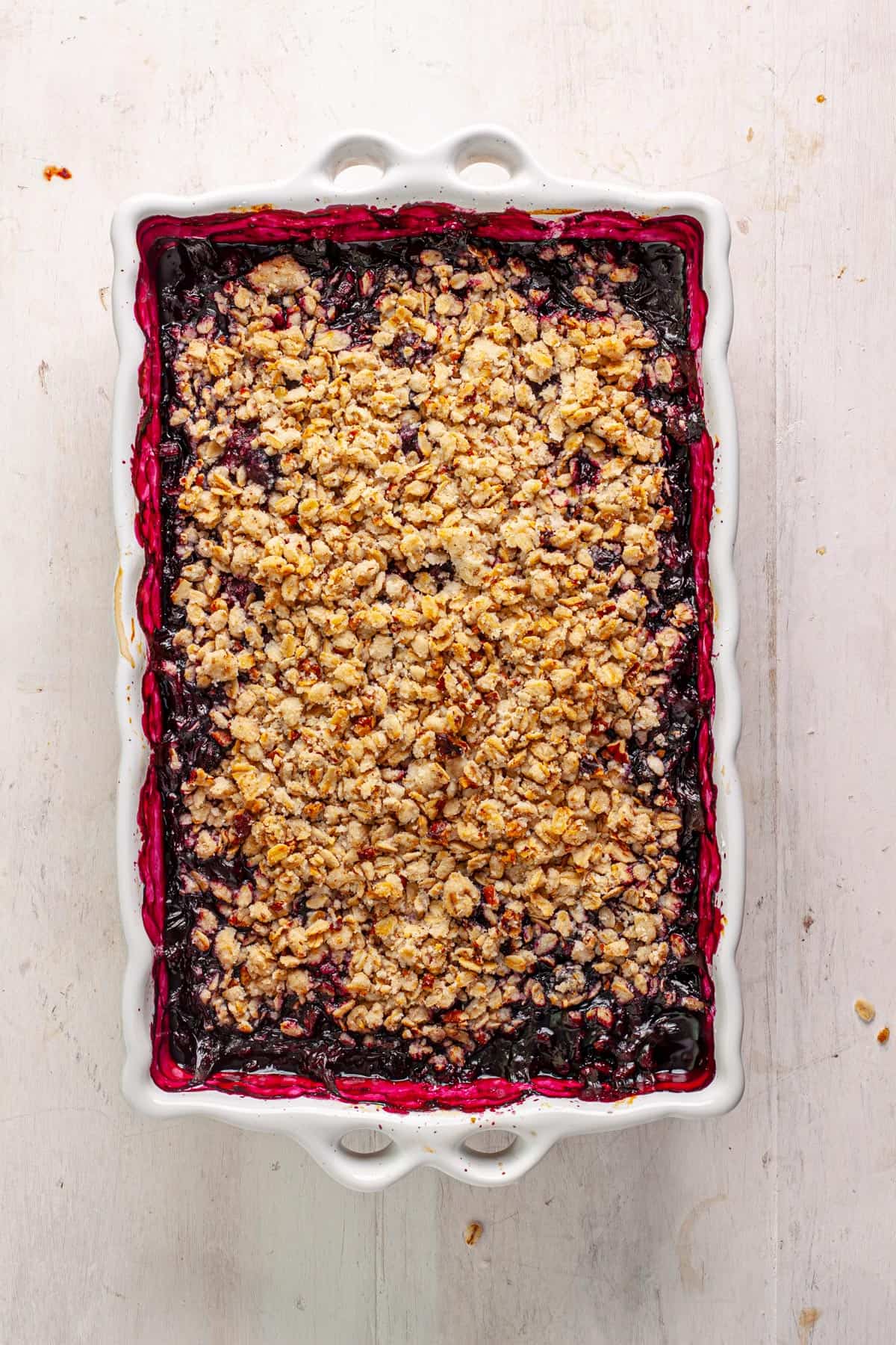 A vegan blueberry crisp in a white baking dish.