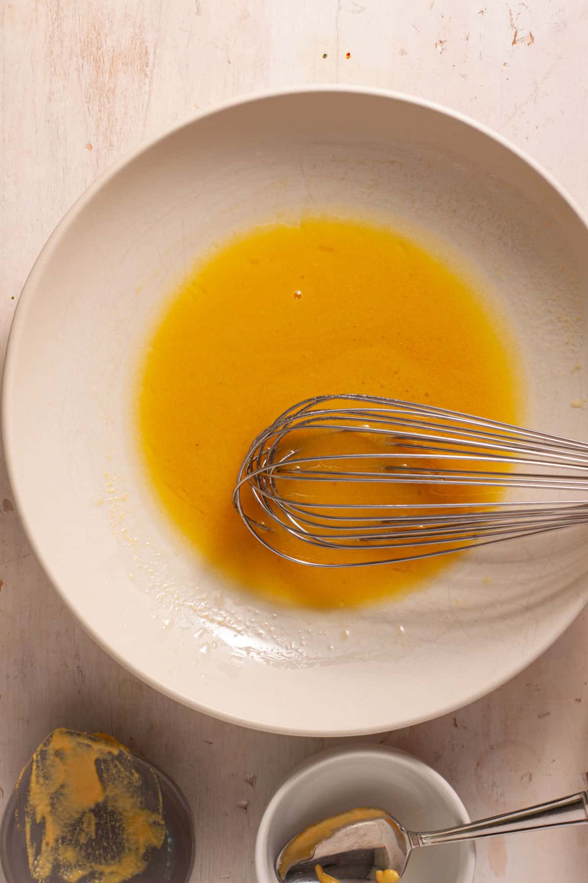 Maple Dijon Dressing getting whisked together in a medium bowl.