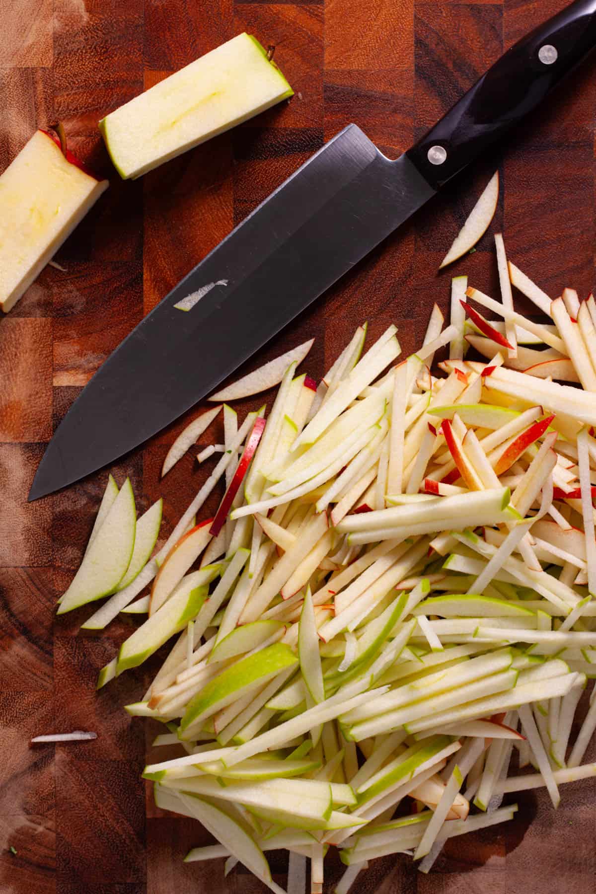 Apples getting cut into matchsticks for a kale and apple slaw.