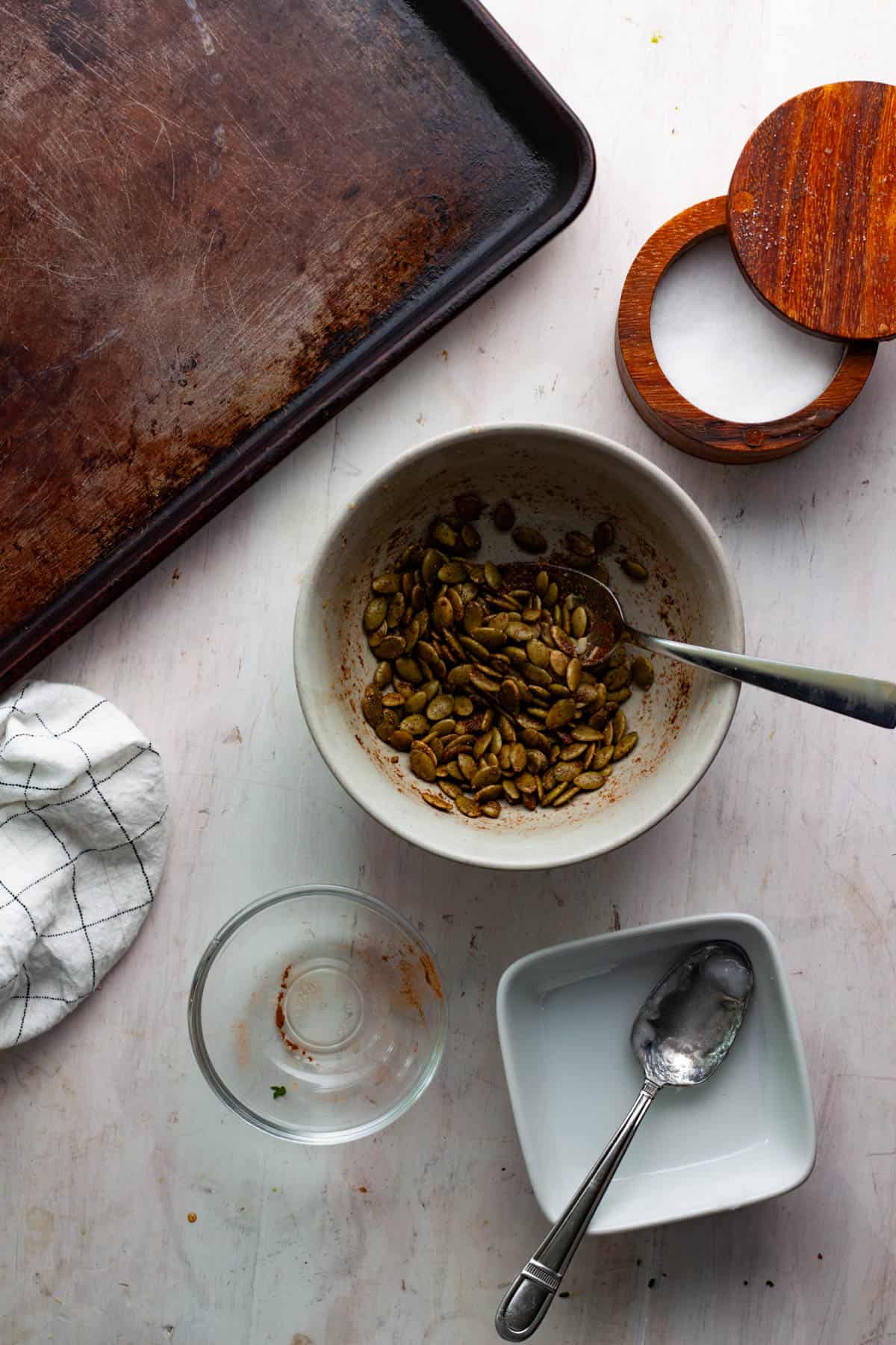 Pepitas in a small bowl with coconut oil, salt, ground cinnamon and coriander.
