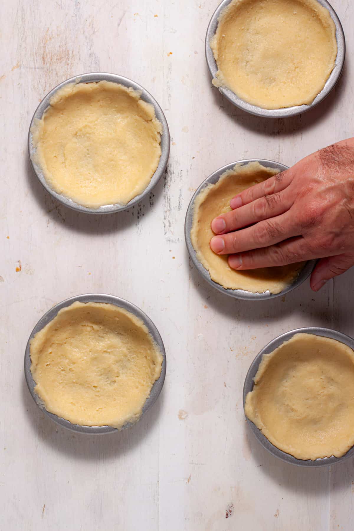 A simple cookie pie crust getting pressed into mini pie pans.