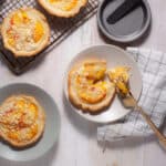 Mini peach custard pies on a small plate with a fork taking a bite out of one.