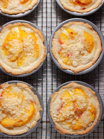 Mini peach custard pies cooling on a wire rack.