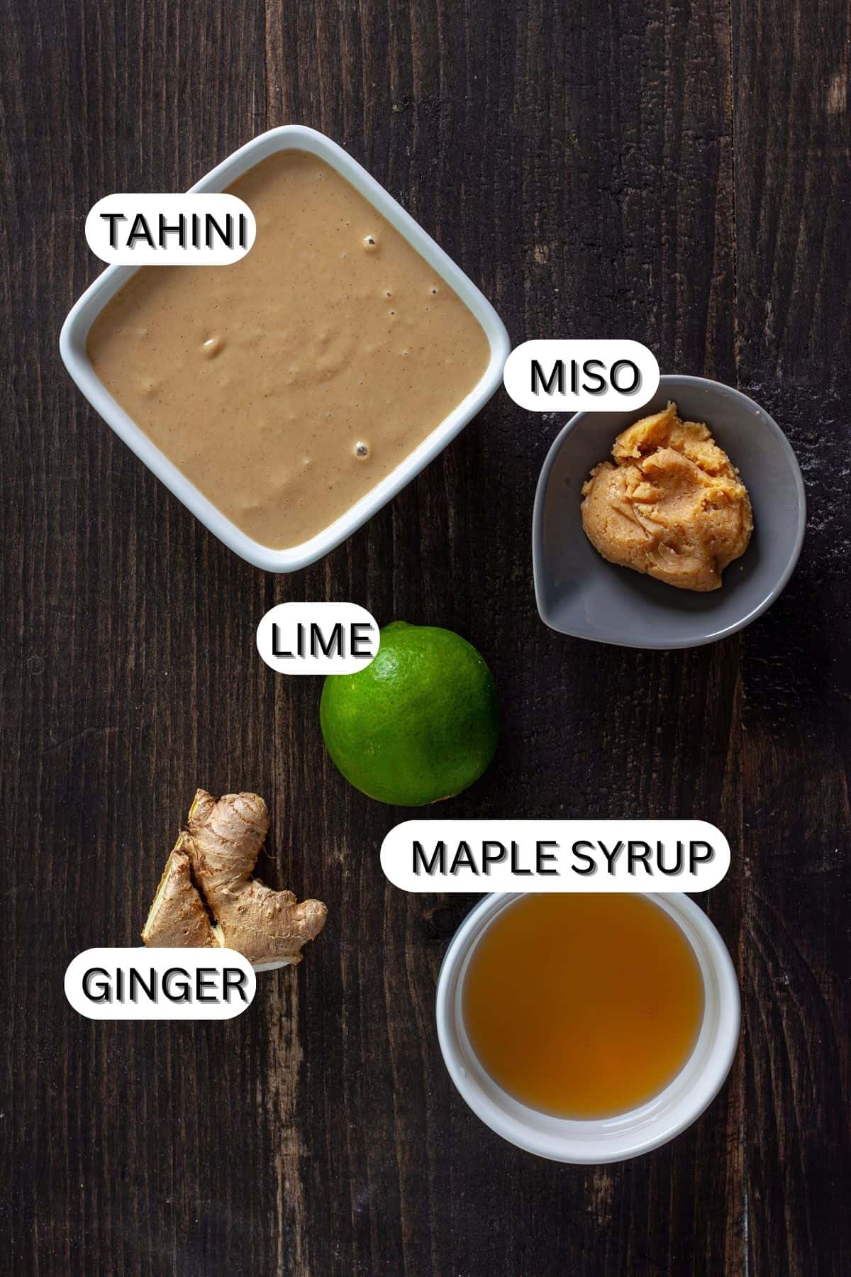 Ingredients for a miso tahini dressing on a dark table.