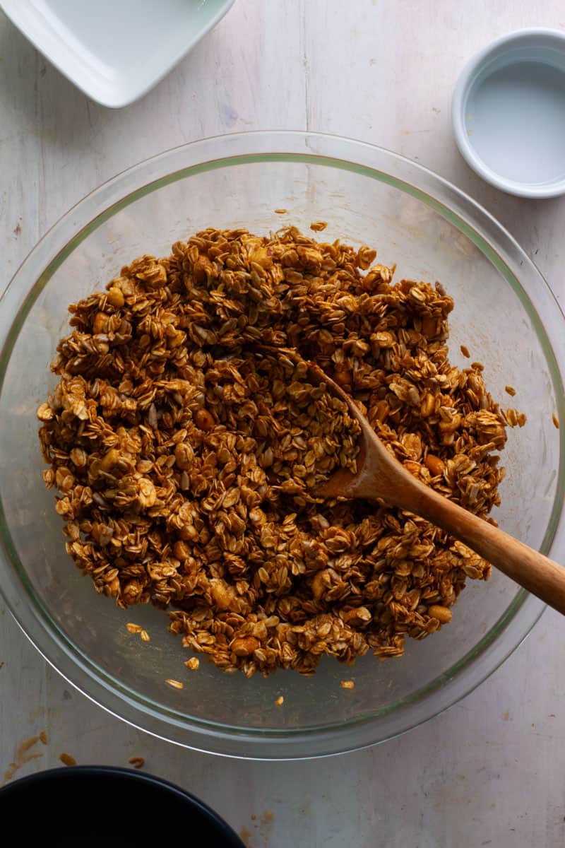Homemade peanut butter granola in a large bowl getting mixed together before baking.