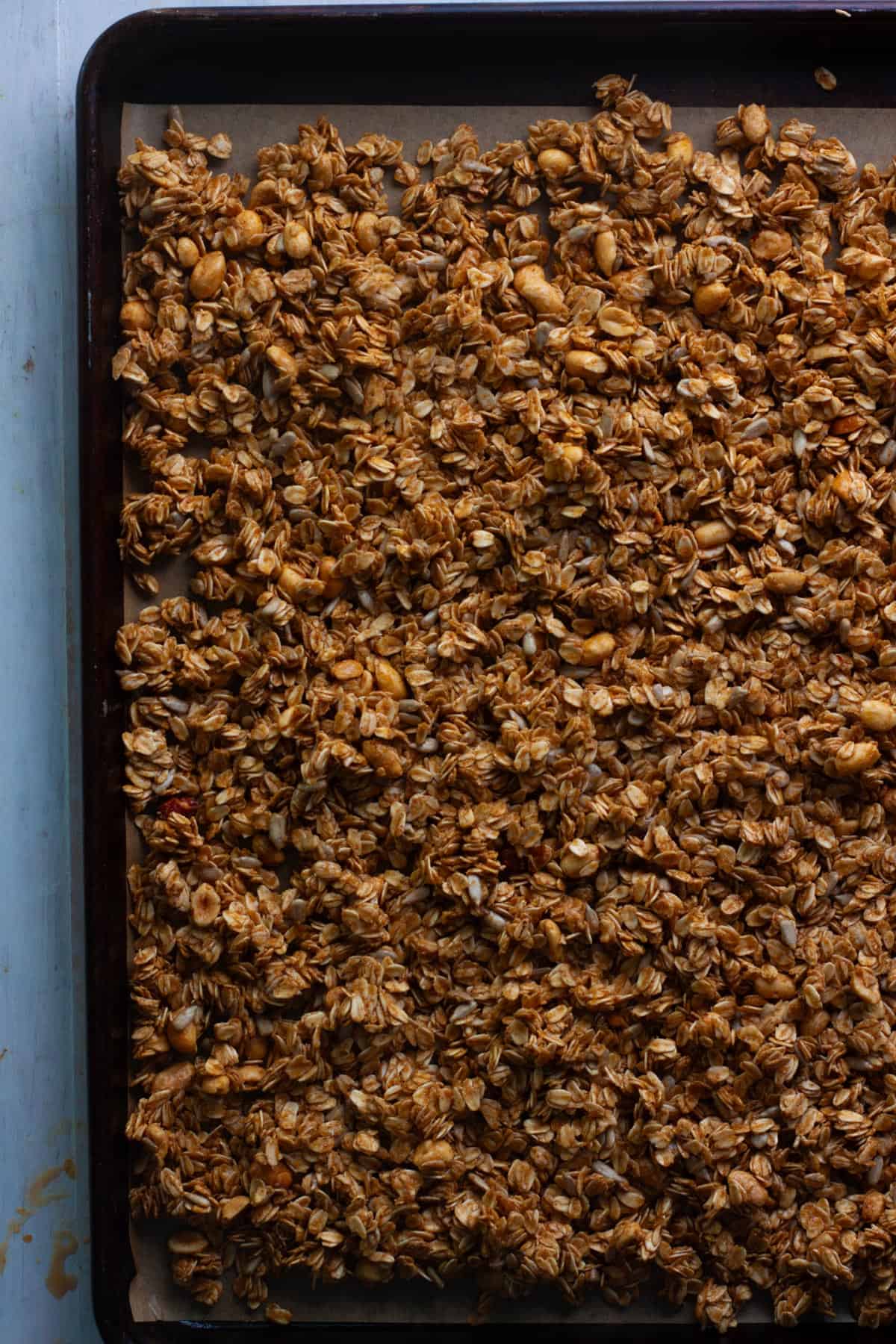 Homemade peanut butter granola on a sheet tray getting ready to get baked.