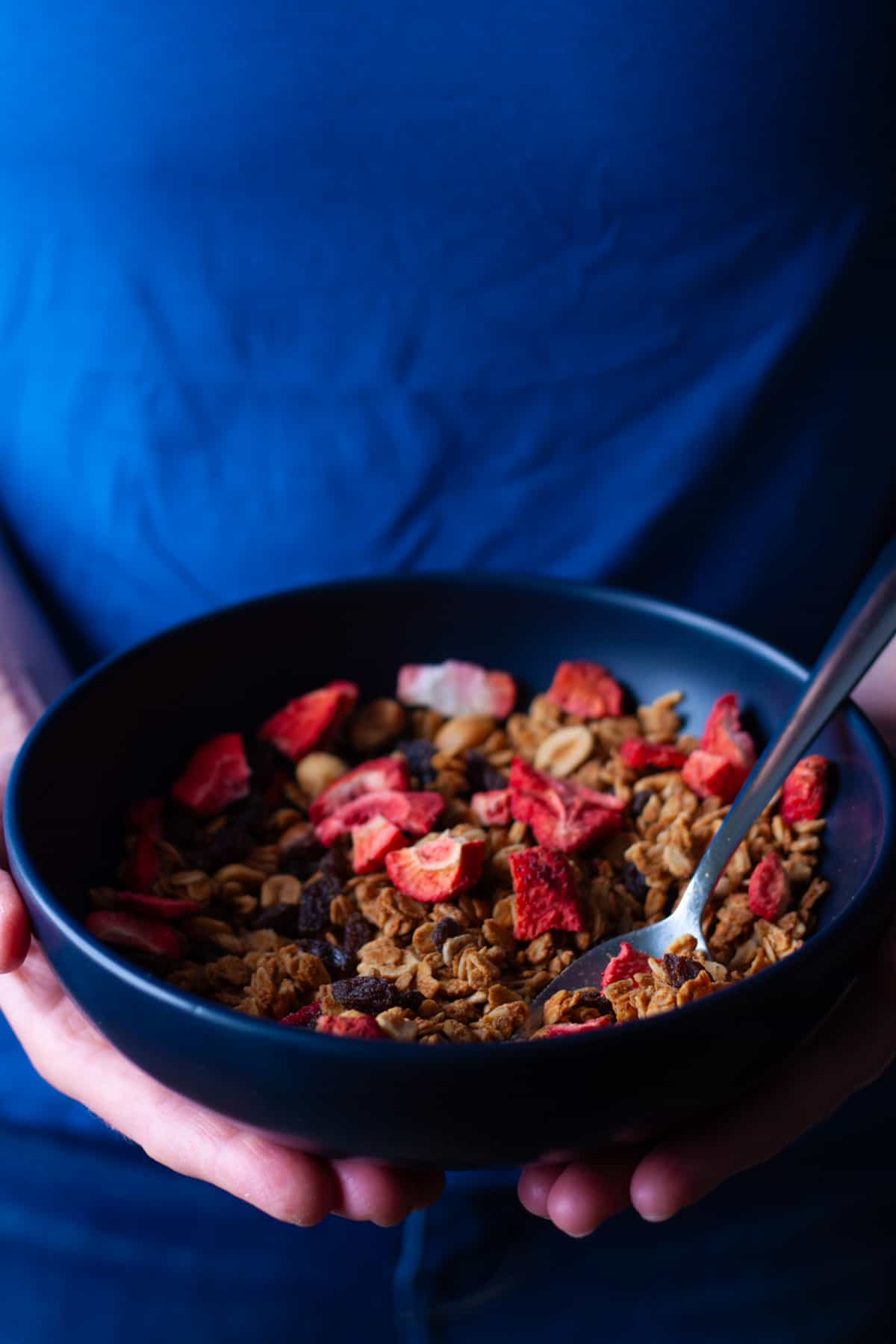 Hands holding a serving of peanut butter granola.