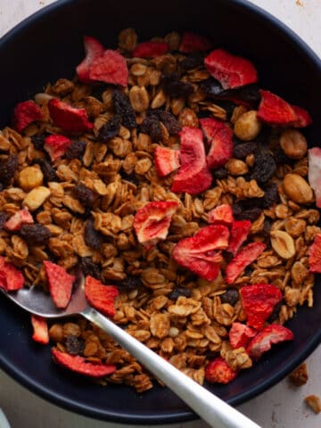 homemade peanut butter granola in a bowl with dried strawberries.