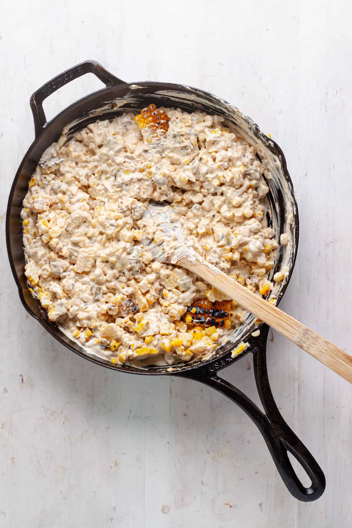 A skillet of street corn dip getting assembled.