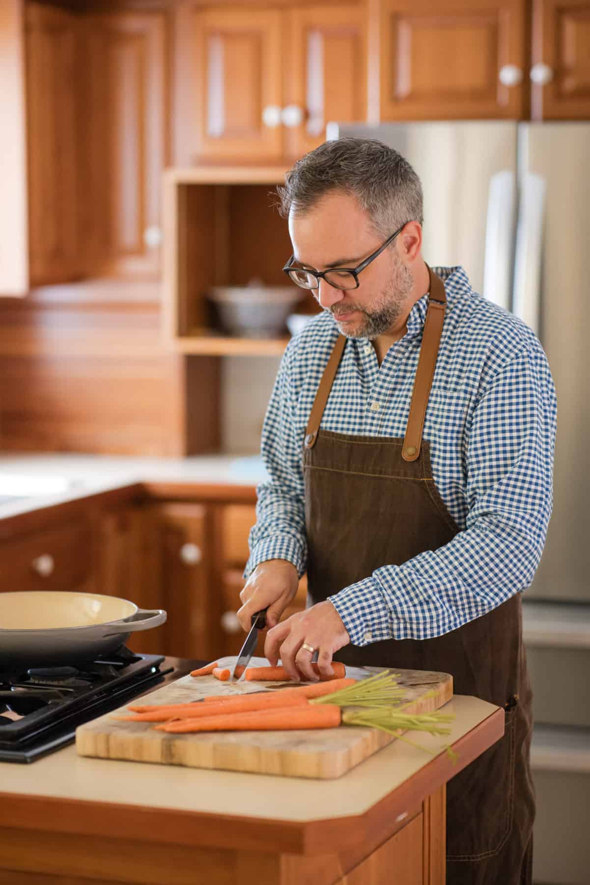 A chef cutting carrots on a cutting board.