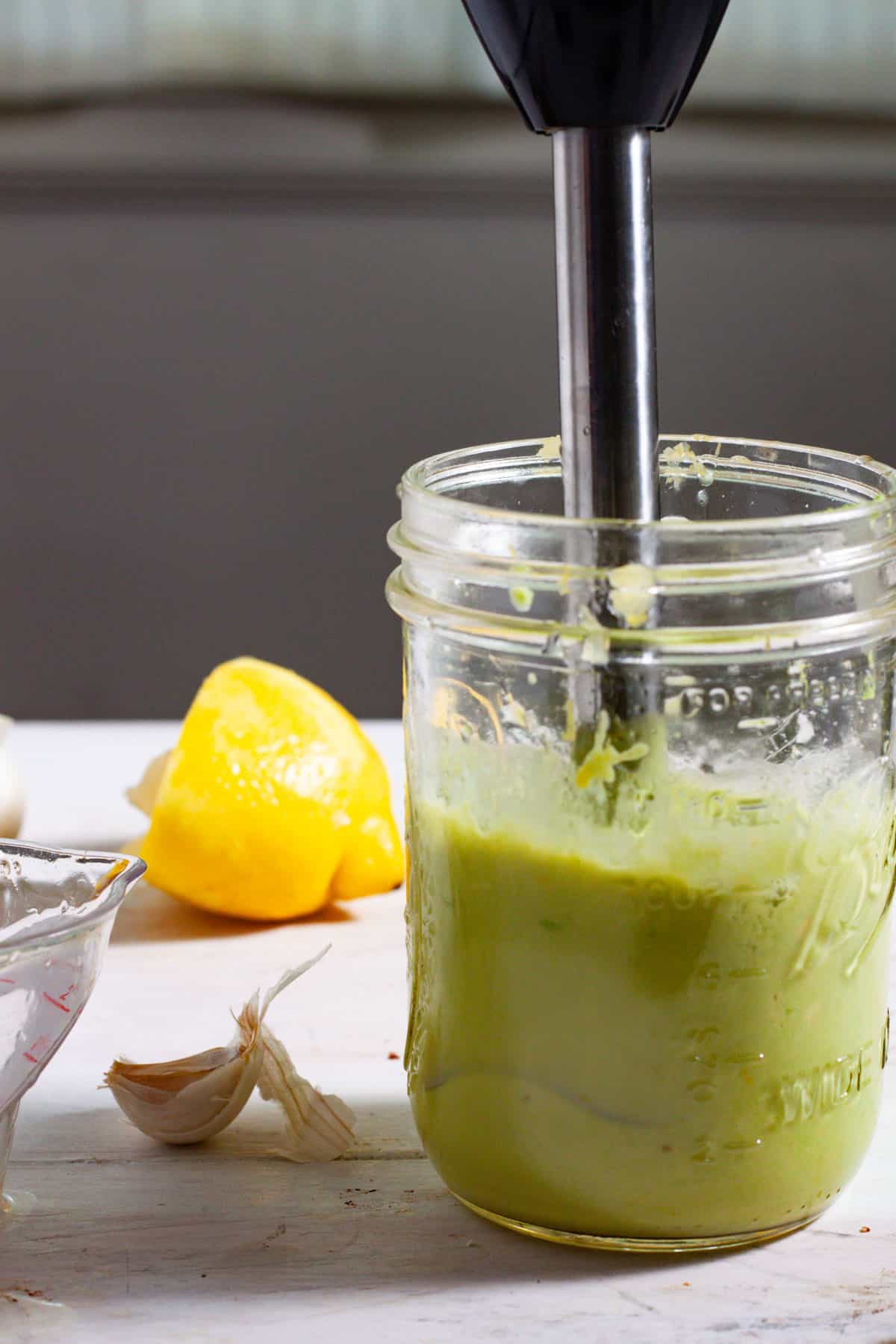 An avocado aioli getting blended together in a mason jar.