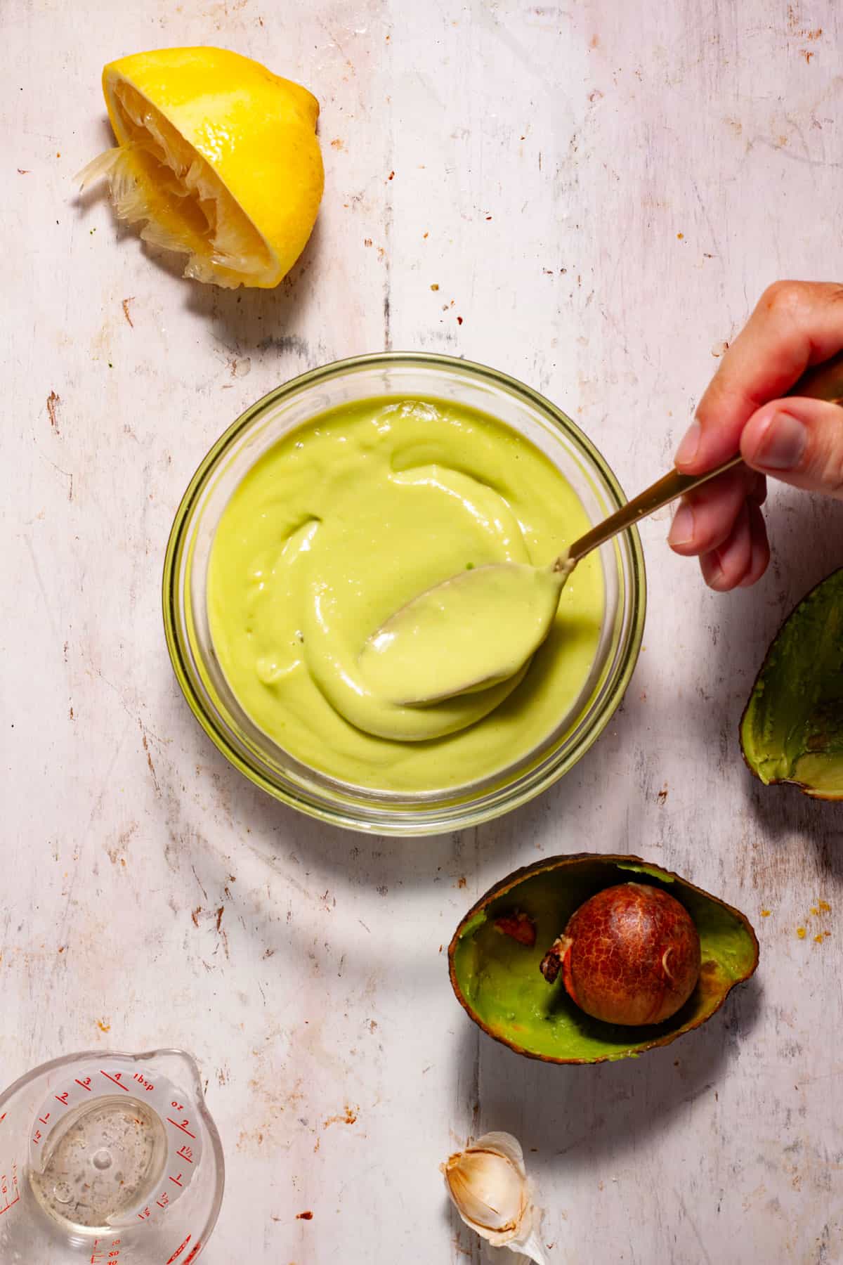 An avocado aioli in a small bowl getting stirred.