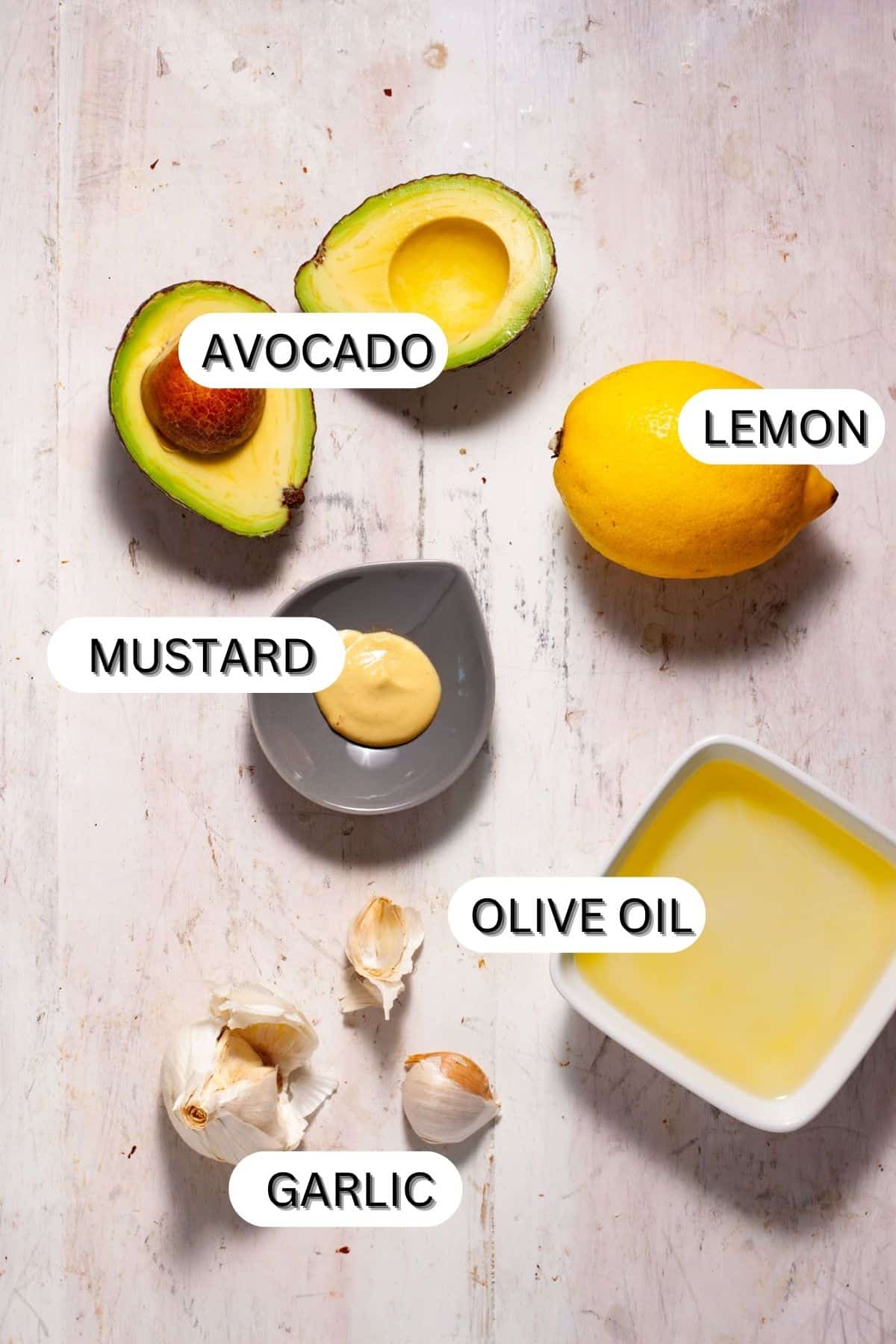 Ingredients for an avocado aioli on a white table.