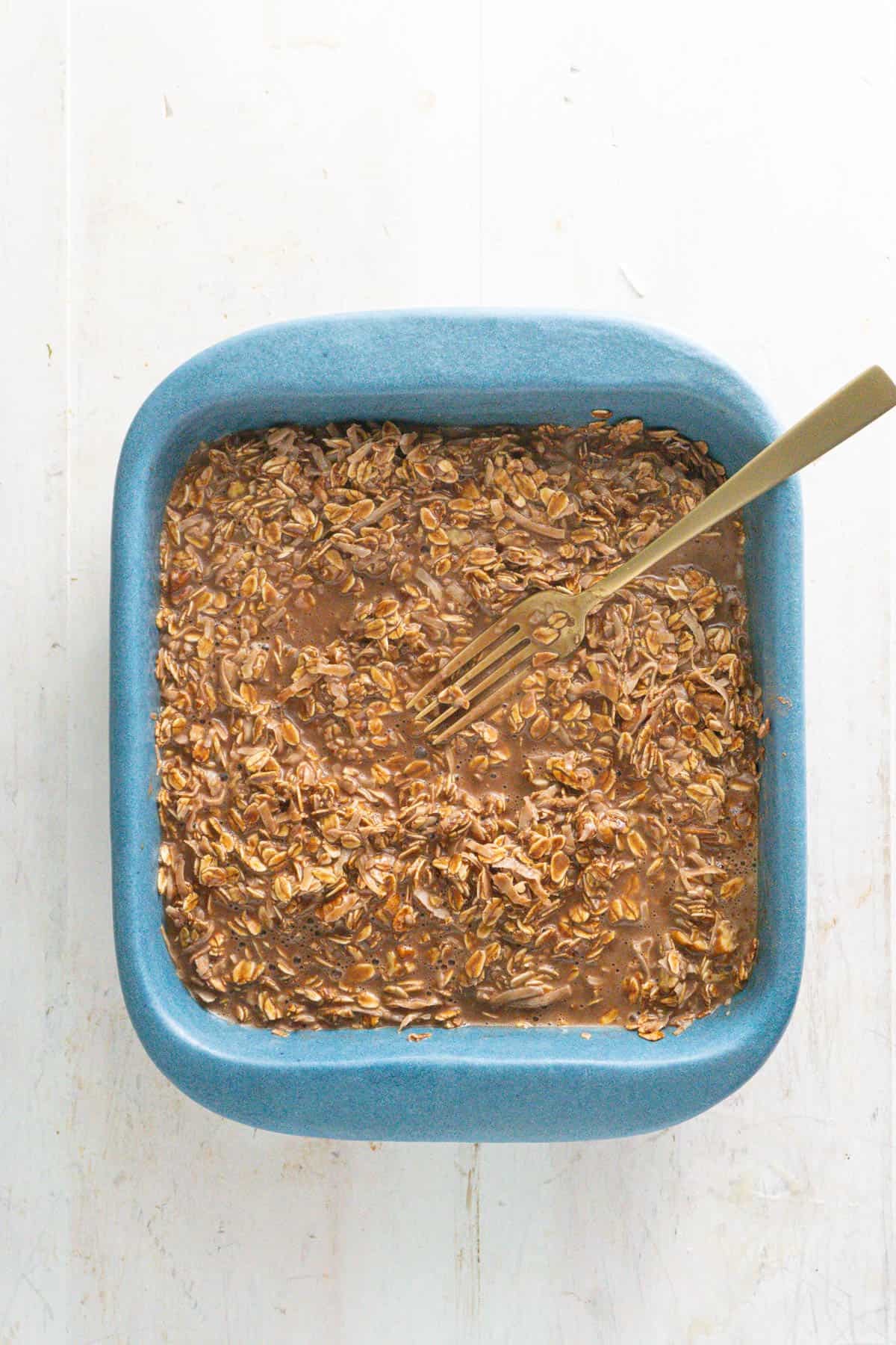 The wet and dry ingredients of a German chocolate cake baked oatmeal in a baking dish.